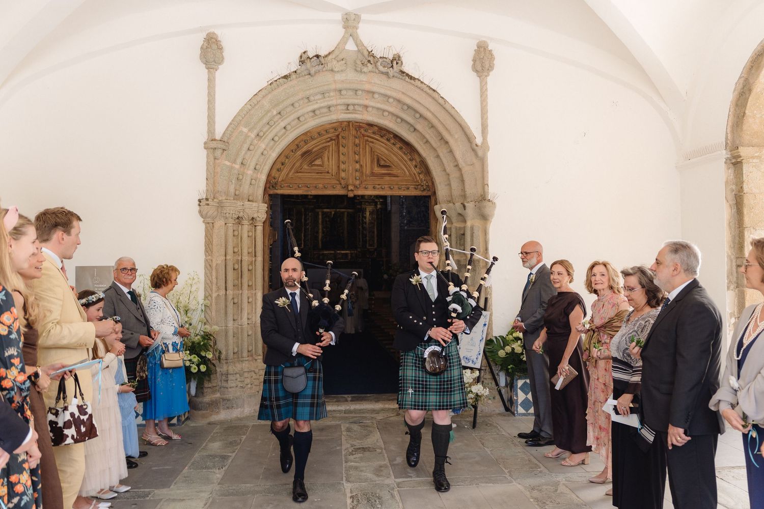 Wedding guests gathering in arched church hallway during ceremony.