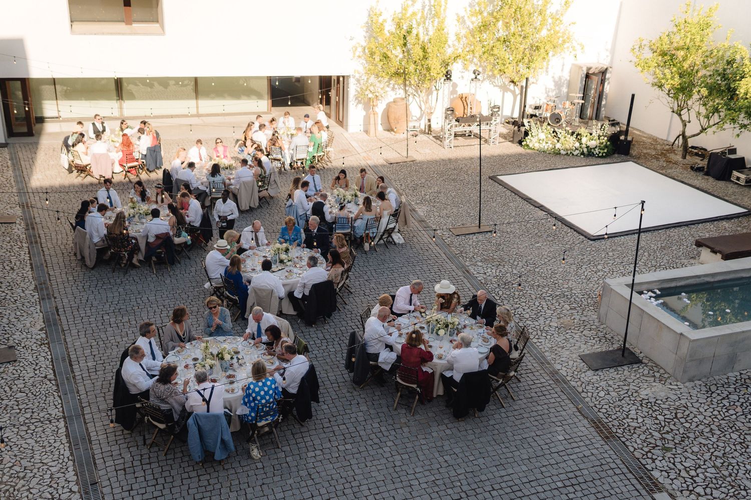 Aerial view of outdoor dining tables arranged in a cobblestone courtyard during a special event.