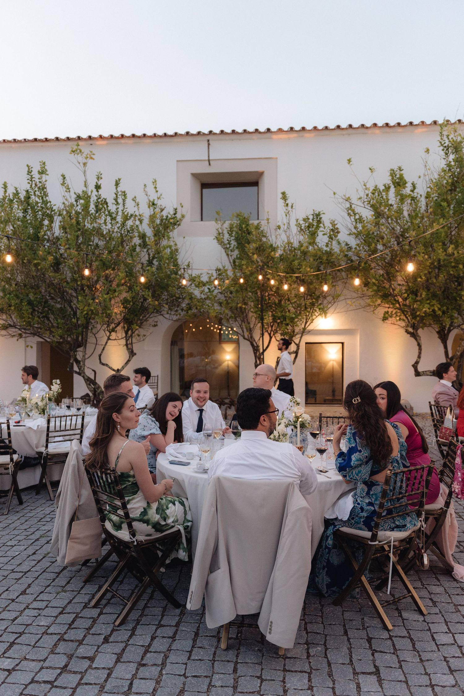 Outdoor dining area with string lights and olive trees creating an intimate Mediterranean atmosphere.