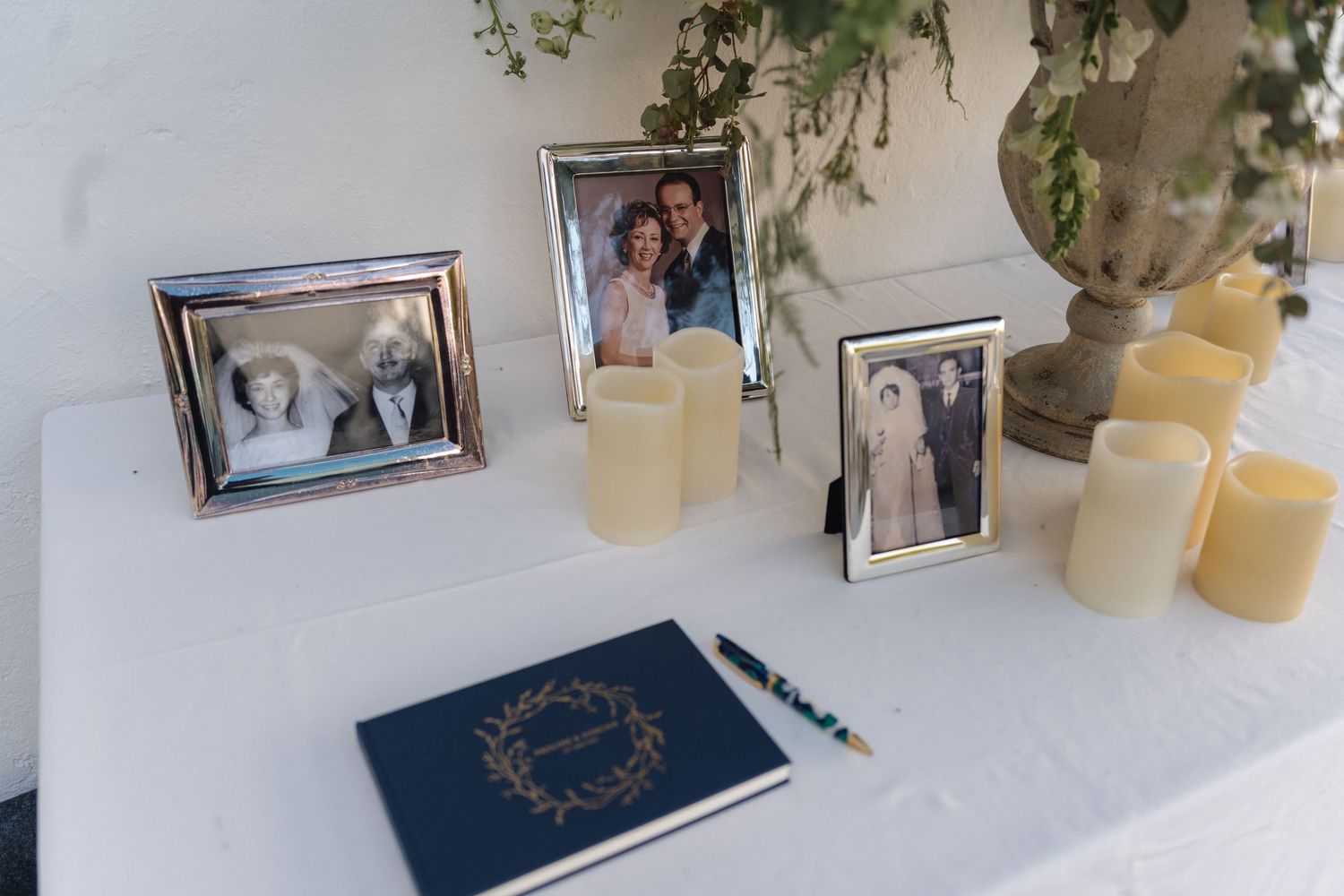 Wedding memorabilia display featuring vintage photographs, candles, and a blue book on white surface.