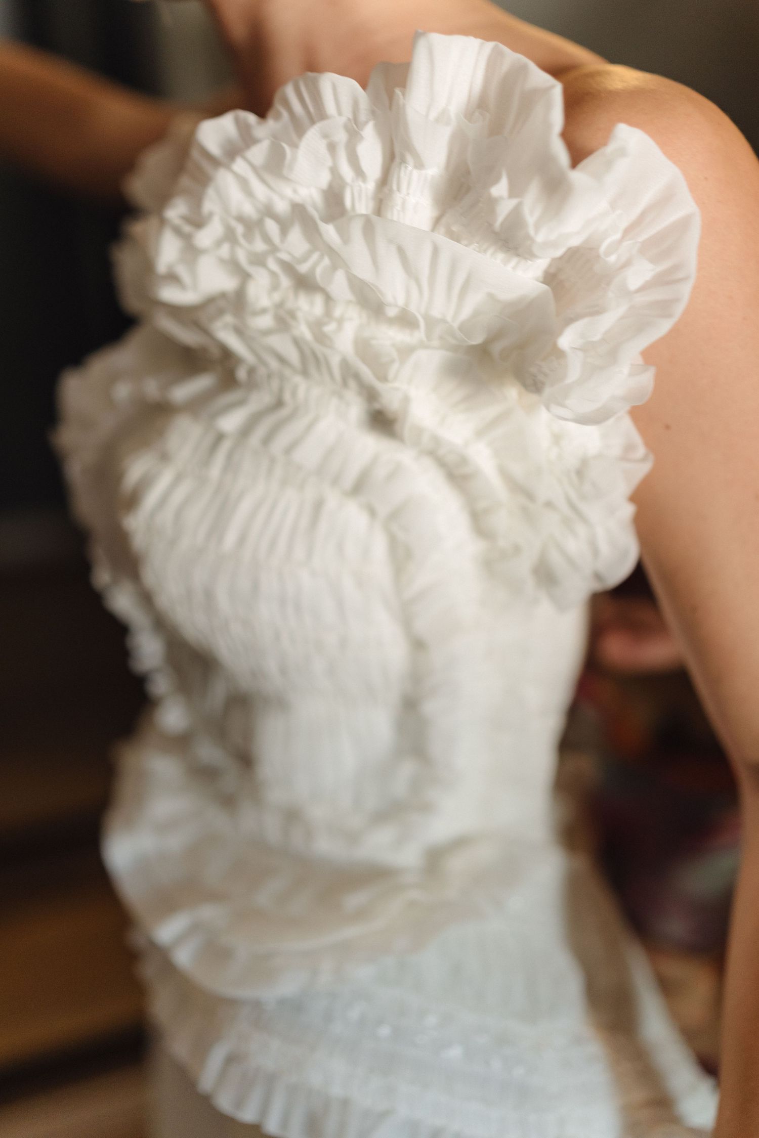 Close-up detail of white ruffled fabric with intricate pleating and texture.