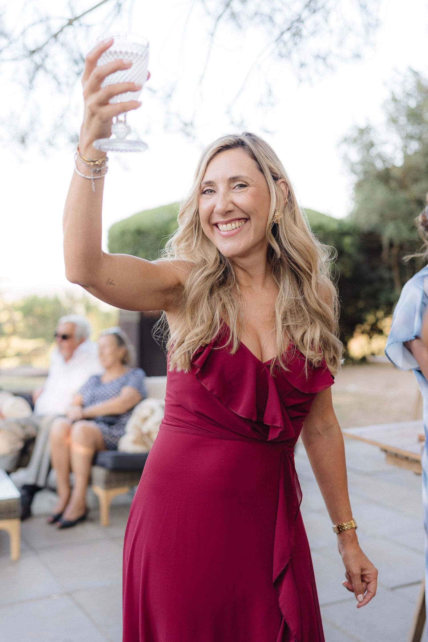 Woman in burgundy dress dancing joyfully at outdoor celebration.