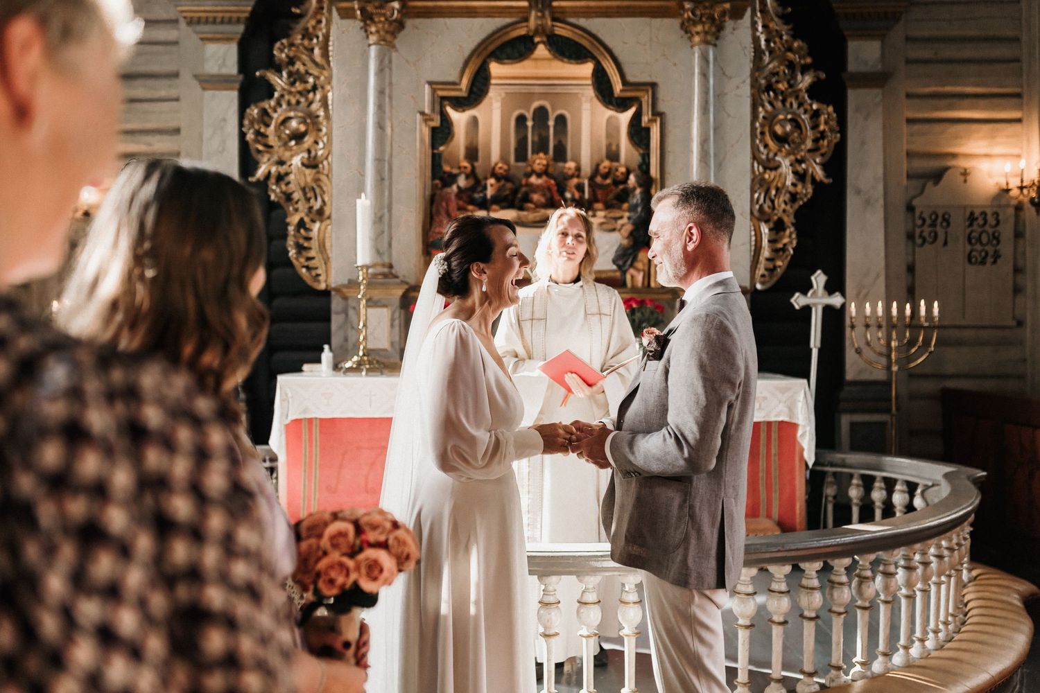 Interior of an ornate church with decorative altar and candles during a wedding ceremony.