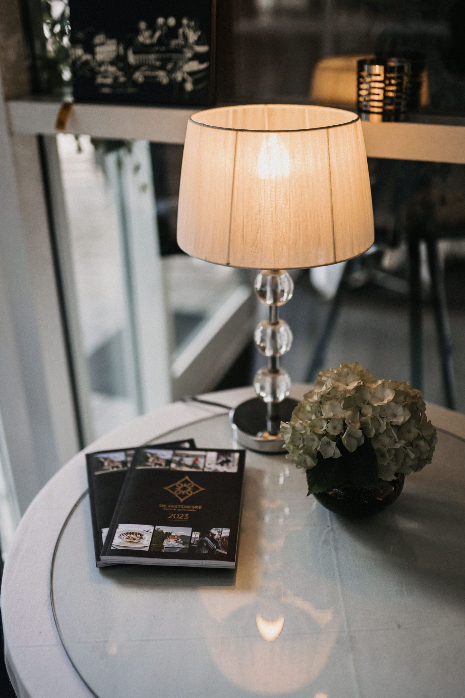 Table setting with elegant table lamp, photo albums and decorative greenery.