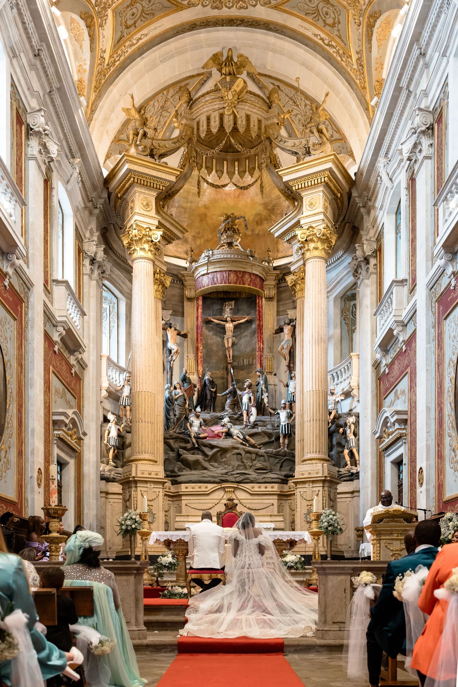 Ornate Catholic church altar with gold details and religious artwork during wedding ceremony.