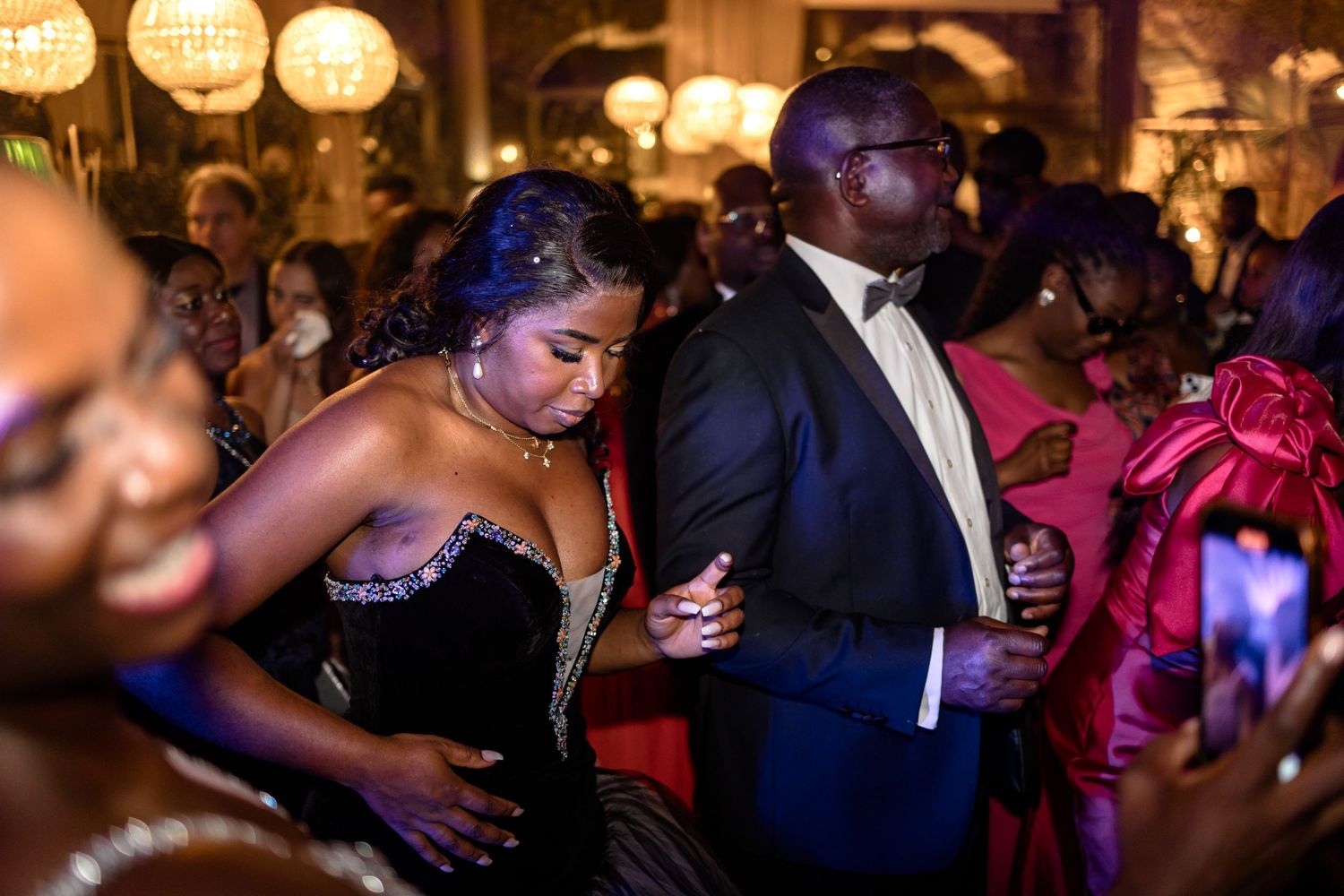 Wedding reception dance floor filled with guests celebrating under glowing lights.