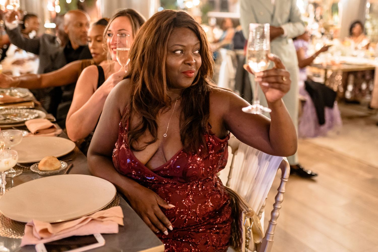 Guest in sparkling red dress enjoying reception dinner.