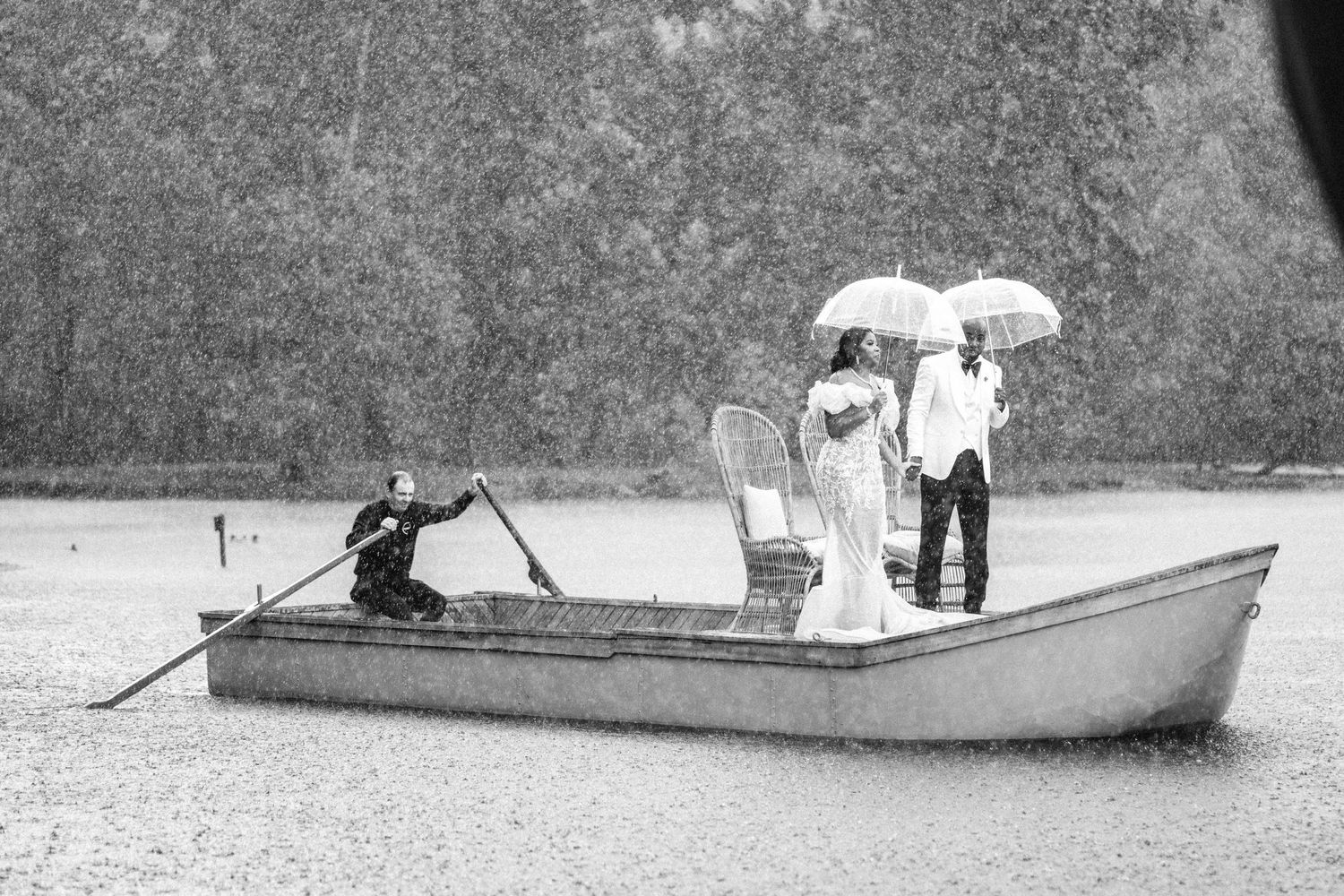Black and white photo of couple in rowboat during rainy wedding photoshoot.