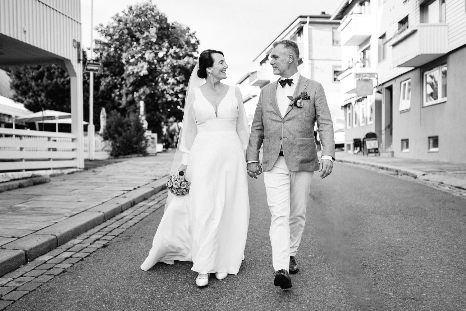 Black and white photo of newlyweds walking together on a street.