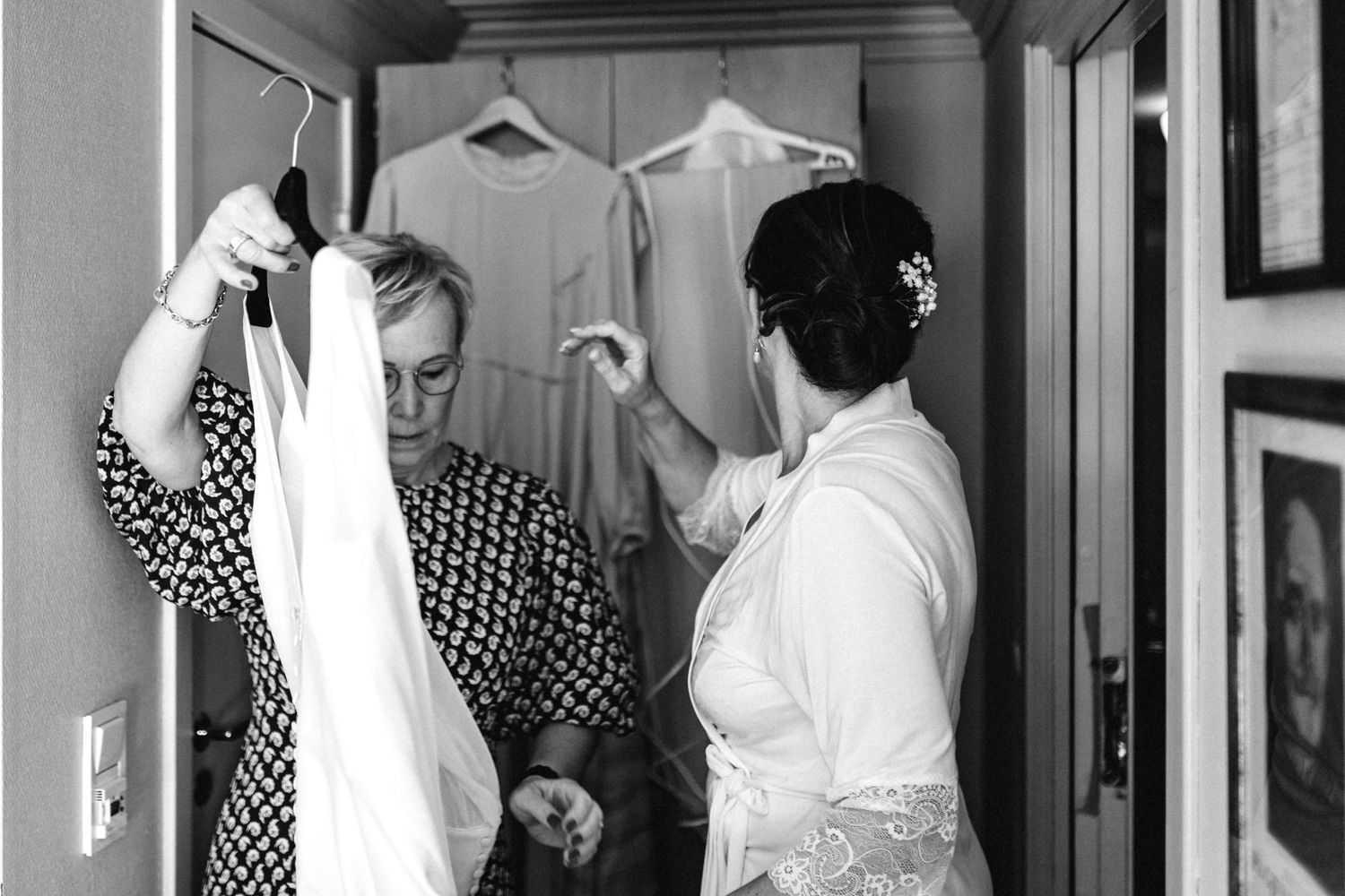 Black and white photo of people getting dressed in a room with mirrors.