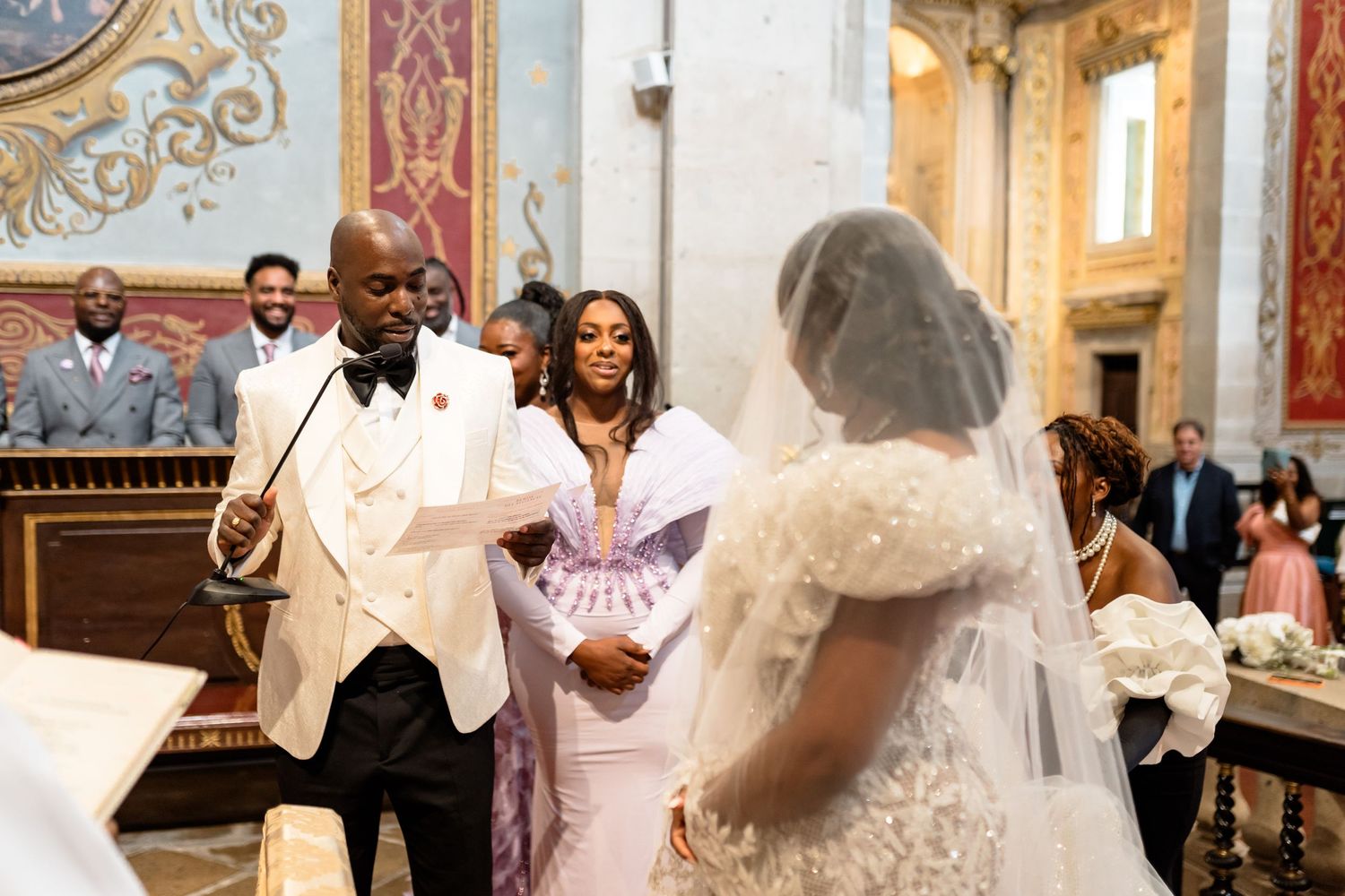 Elegant wedding ceremony in ornate venue with decorative architectural details.