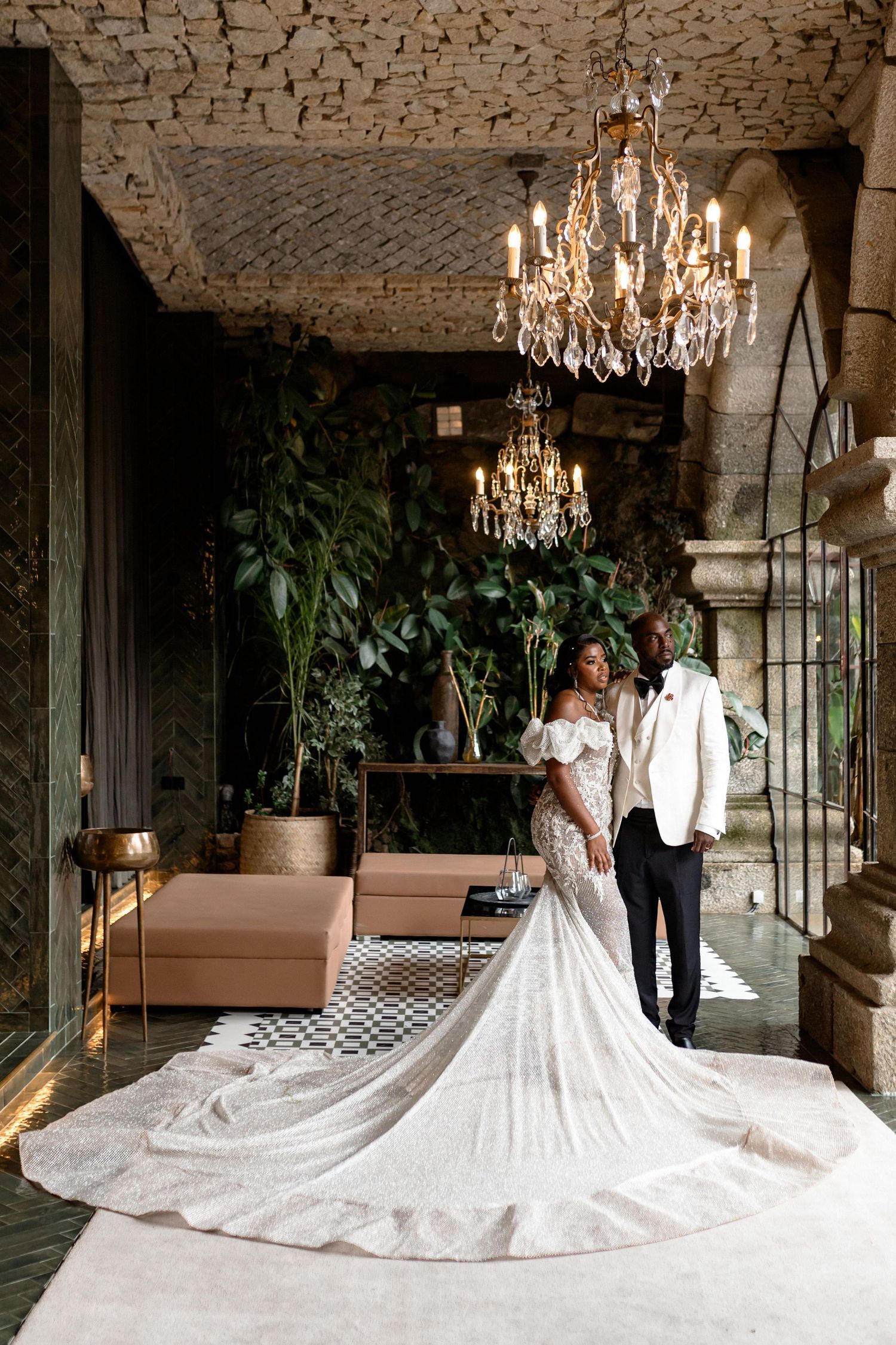 Bride's dramatic cathedral train displayed in elegant stone room with chandeliers.