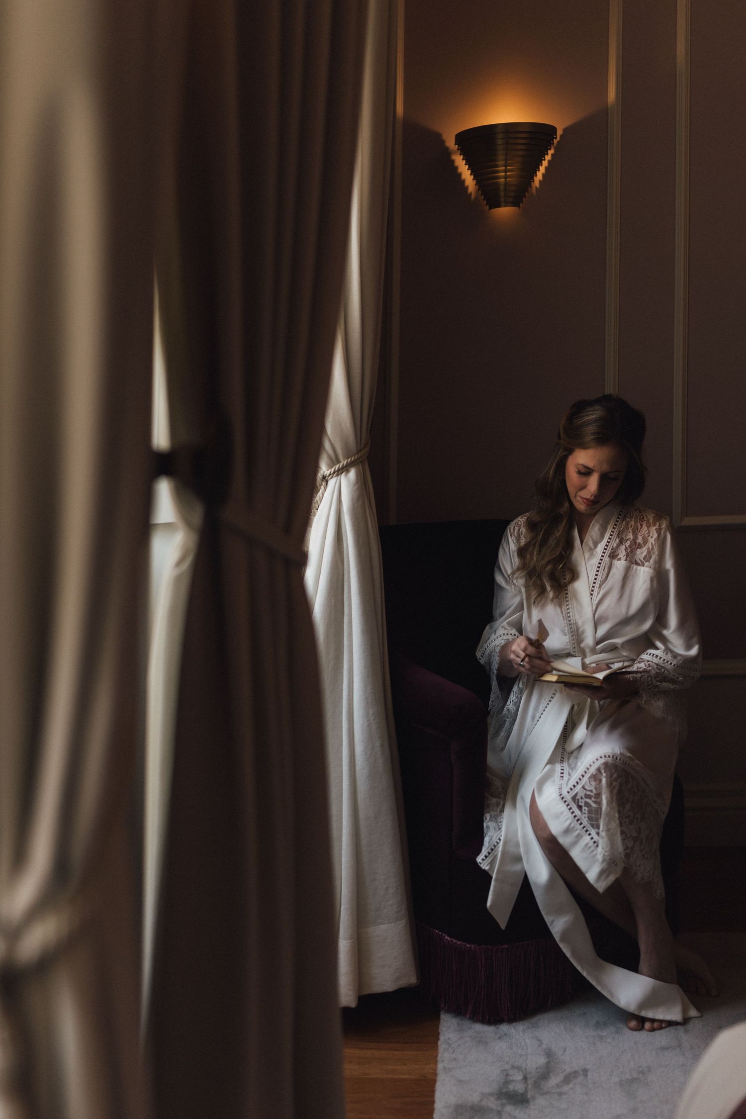 Moody interior shots of someone in white clothing by curtained windows.