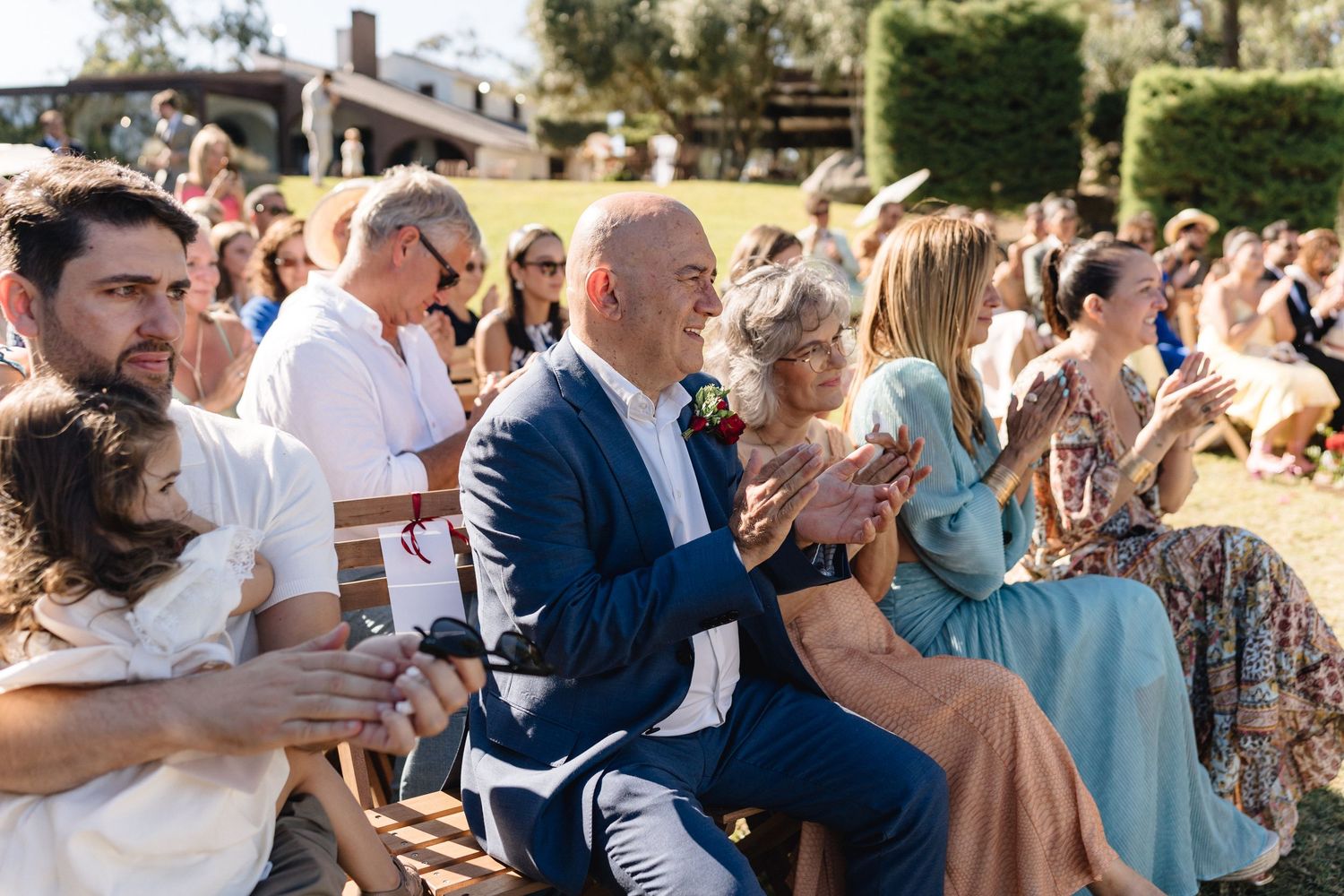 Wedding guests celebrate during an outdoor reception on a sunny afternoon.