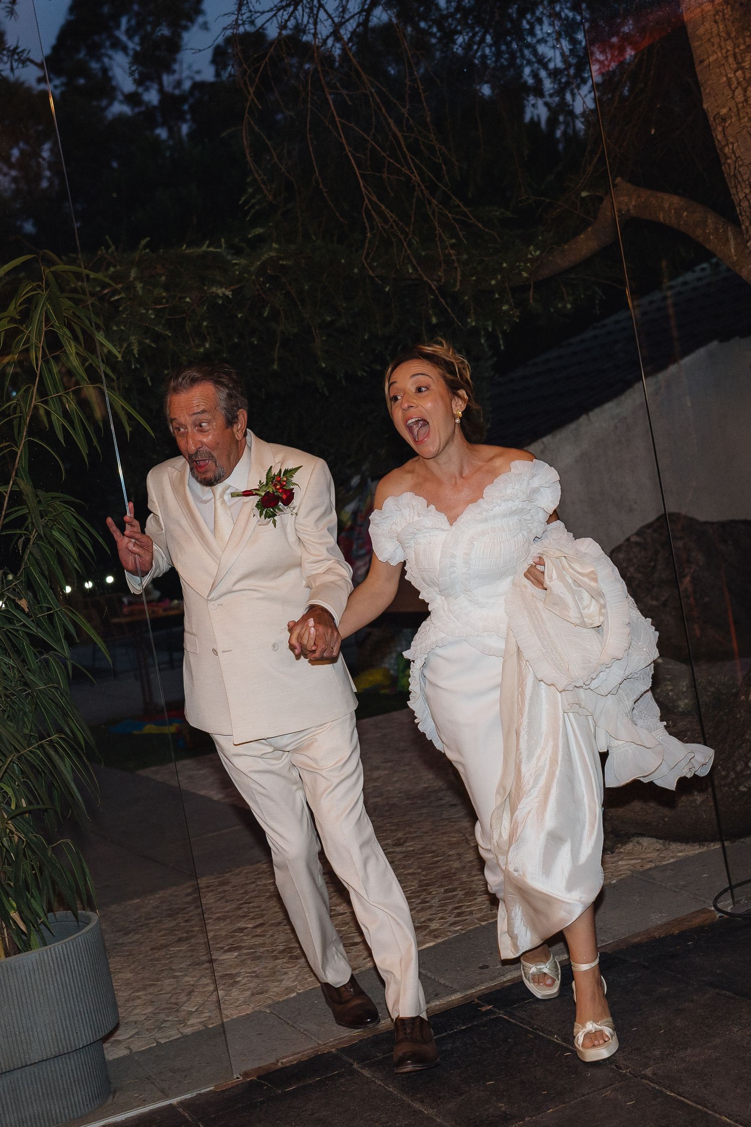 Wedding couple performs energetic dance moves together at evening reception.