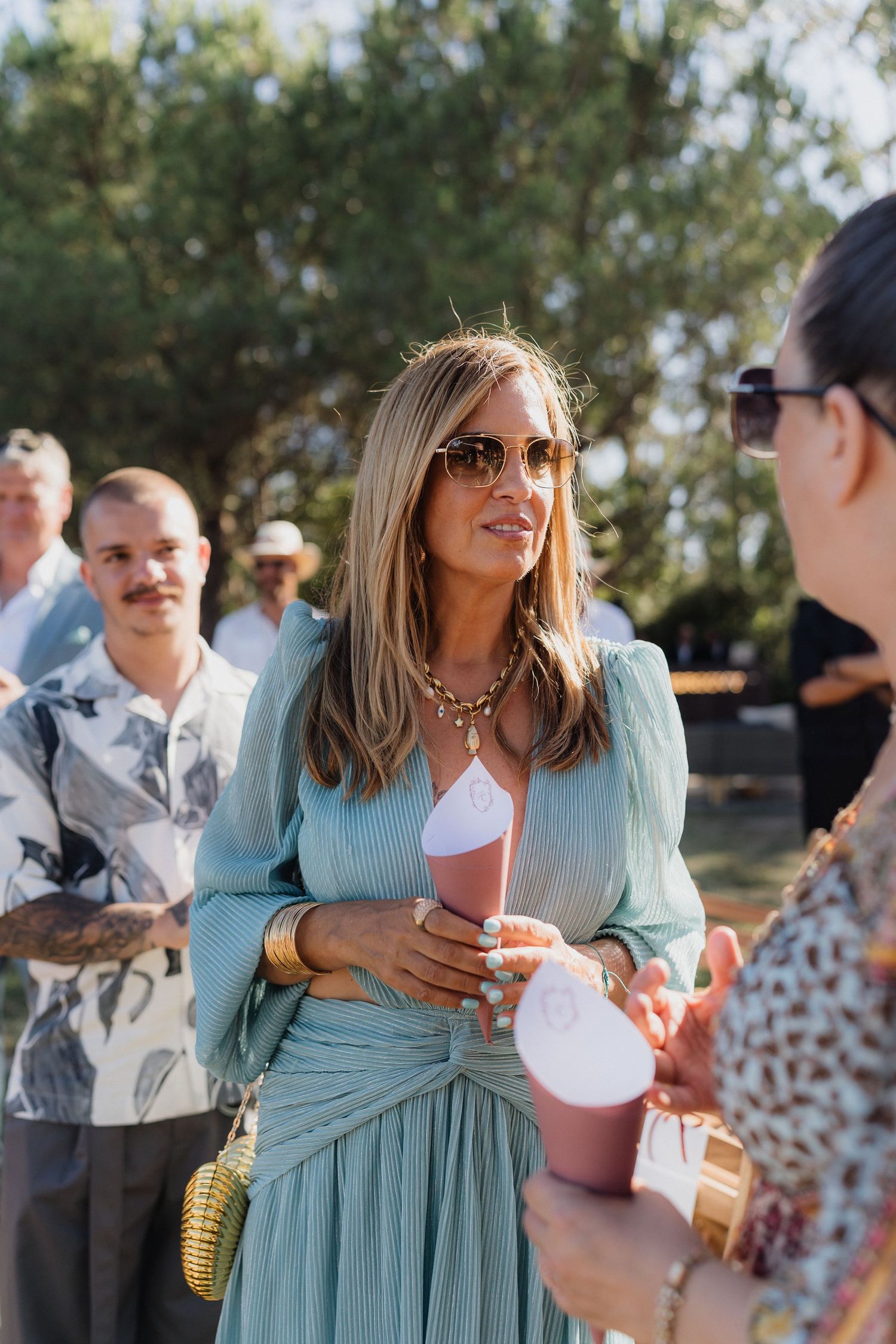 Wedding guests in summer attire mingle and socialize during the outdoor reception.