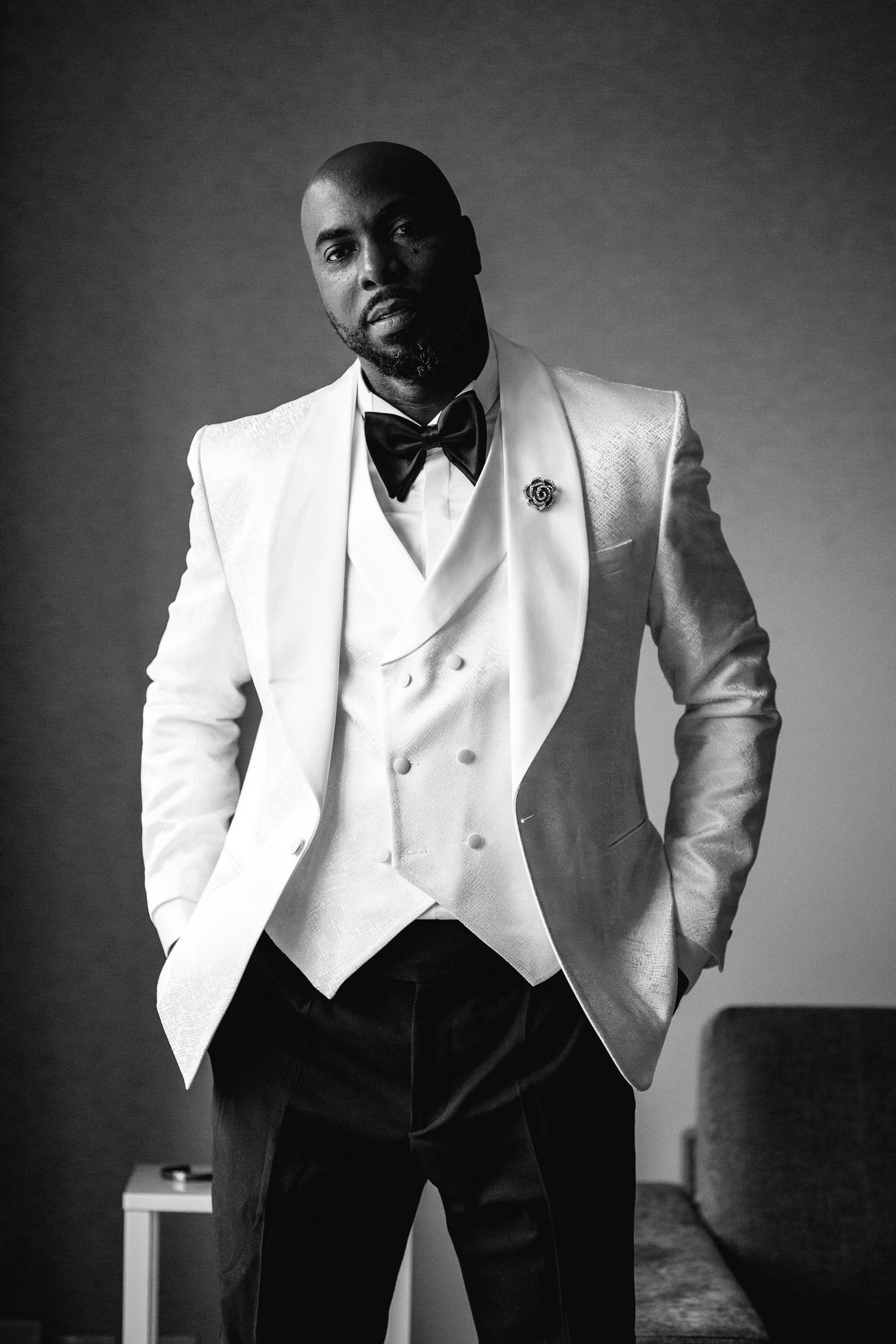 Dramatic black and white portraits of groom in formal white tuxedo jacket.