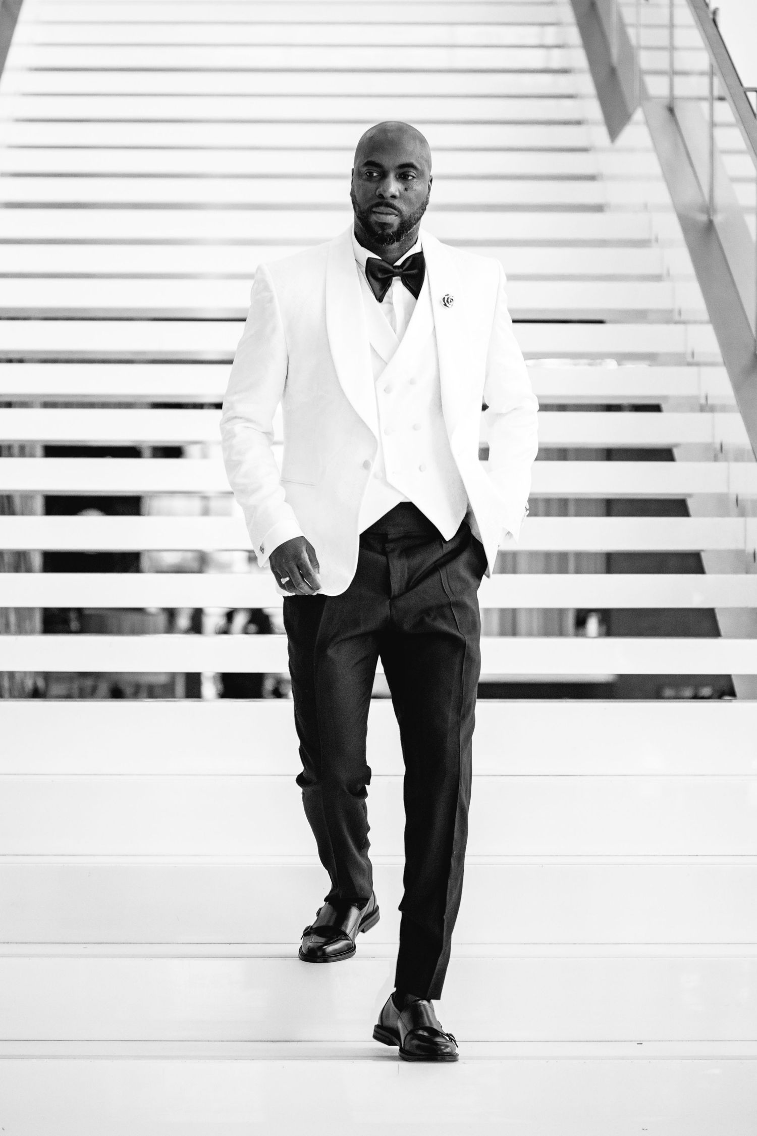A sequence of black and white photos showing someone walking down white stairs with modern architecture.