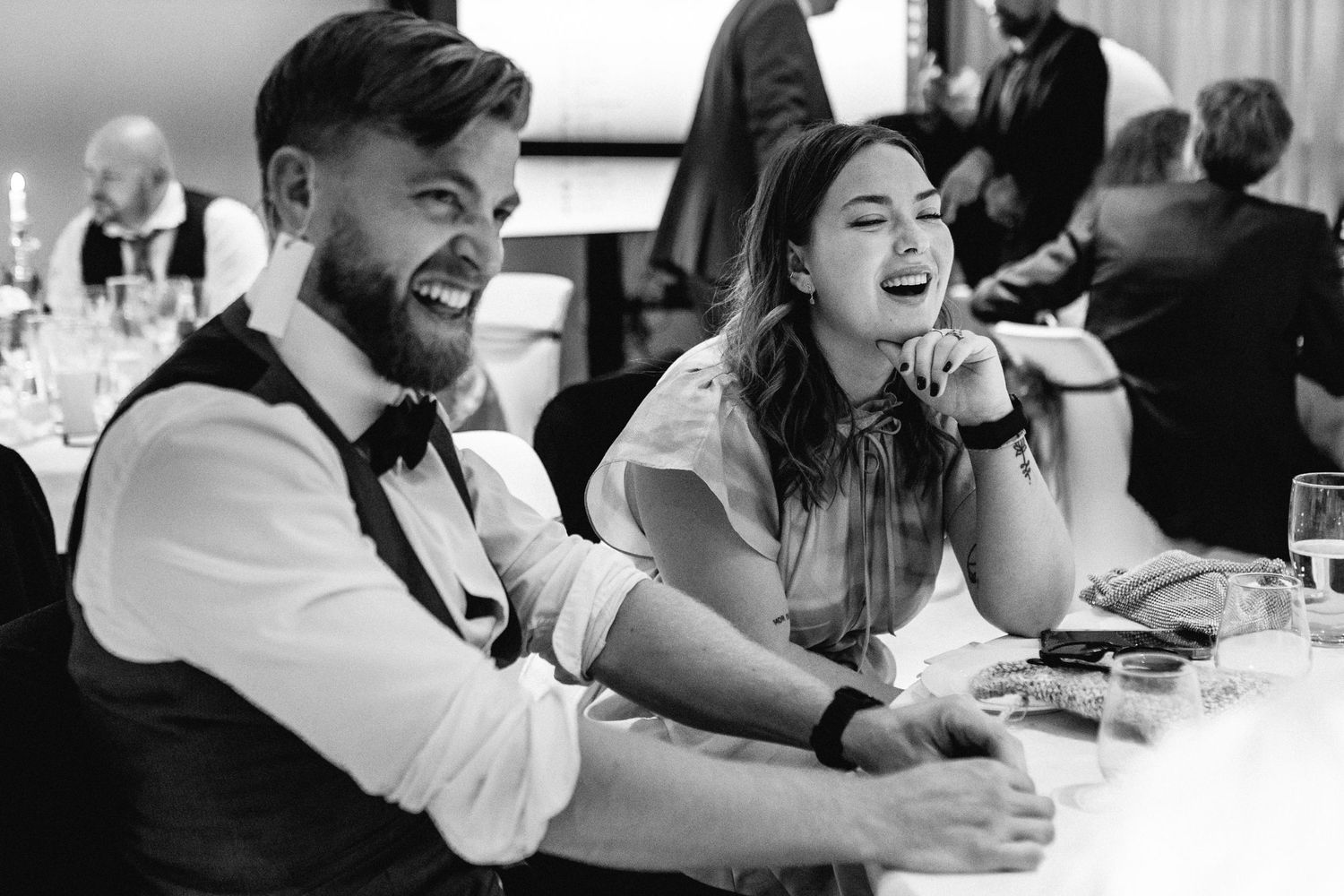 Black and white candid shots of wedding guests laughing during reception.