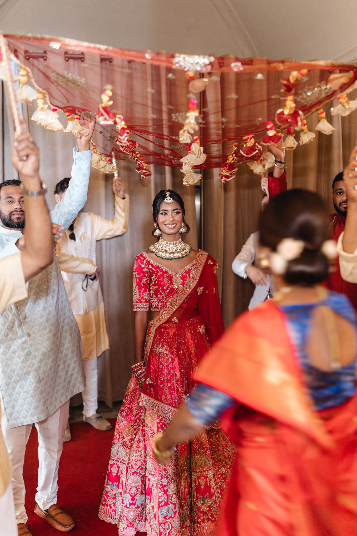Festive indoor celebration with red and white decorations and traditional Indian attire.
