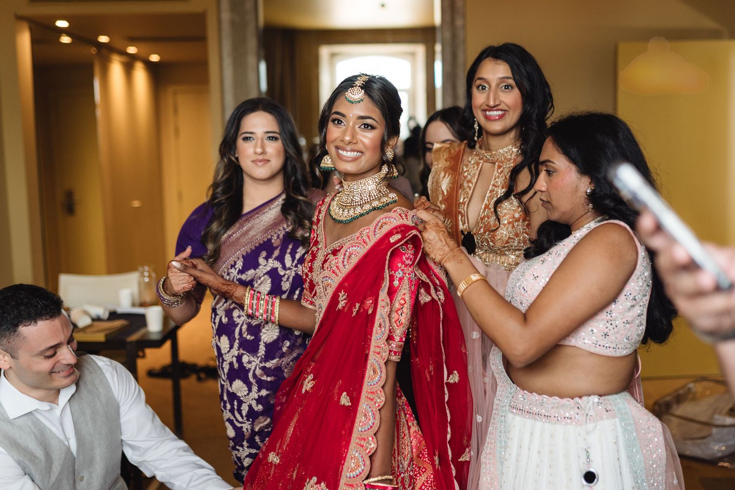 Wedding preparation scene with guests in colorful traditional Indian attire.