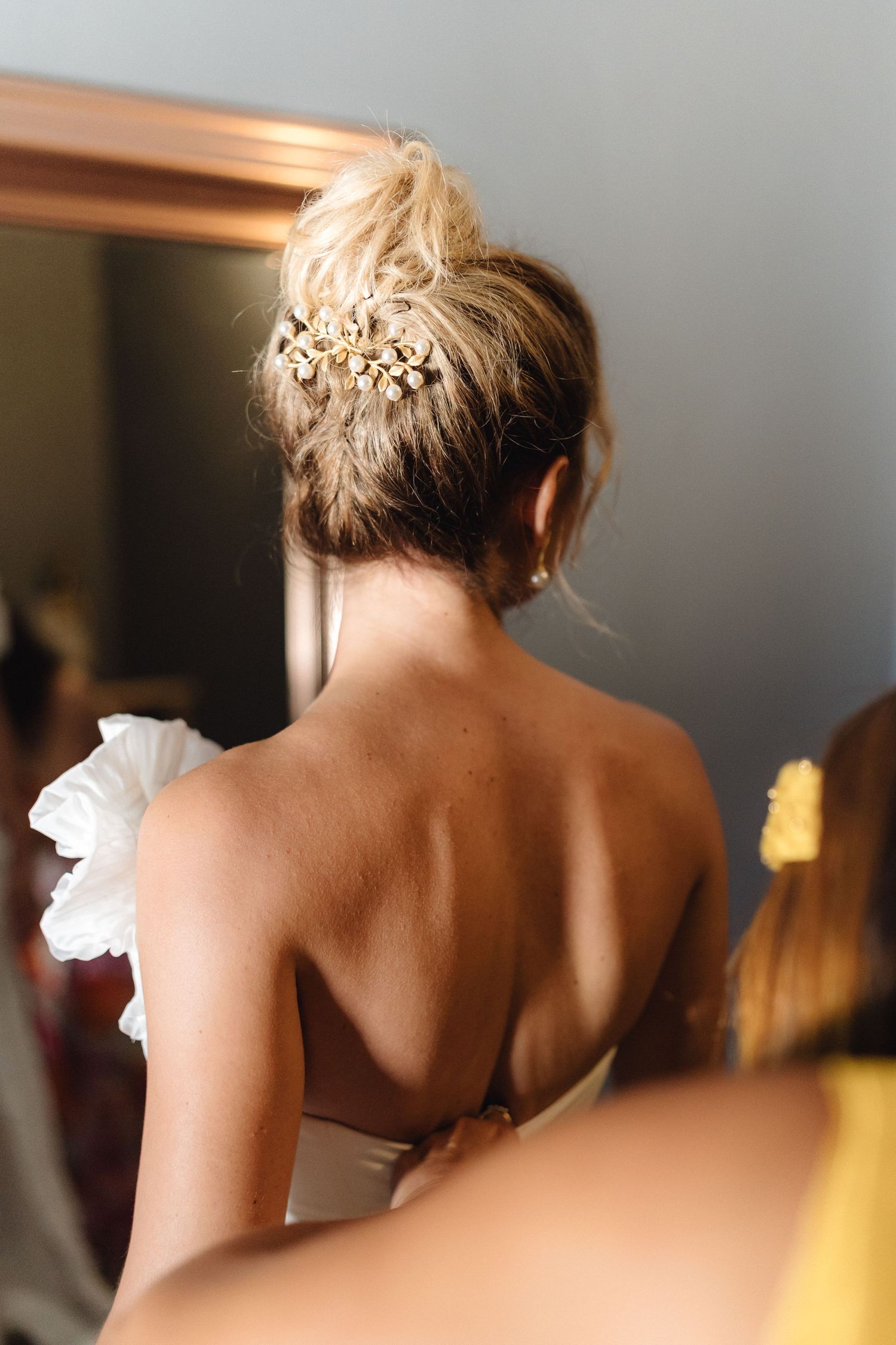 Side view of an elegant bridal hairstyle with floral accessories against a soft background.