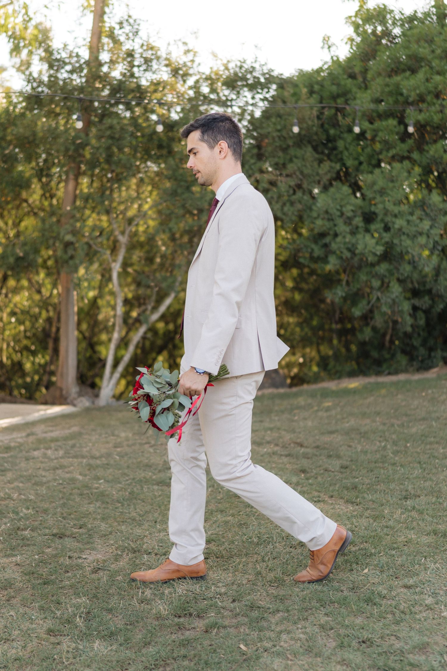 Person in light colored outfit walks playfully across grassy outdoor area.