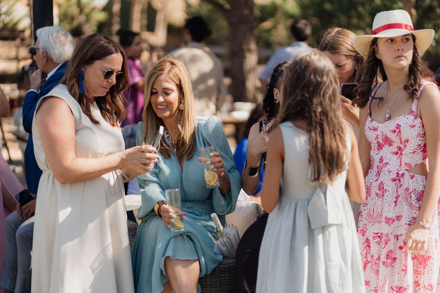 Wedding party members in blue and floral dresses mingling at outdoor celebration.