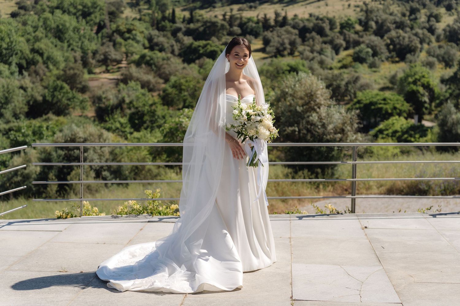 Wedding dress train trailing across stone terrace with mountain landscape in background.