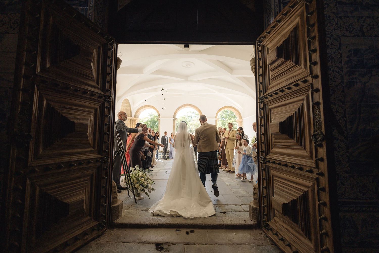Dark wooden church doors frame wedding ceremony exit in dramatic lighting.