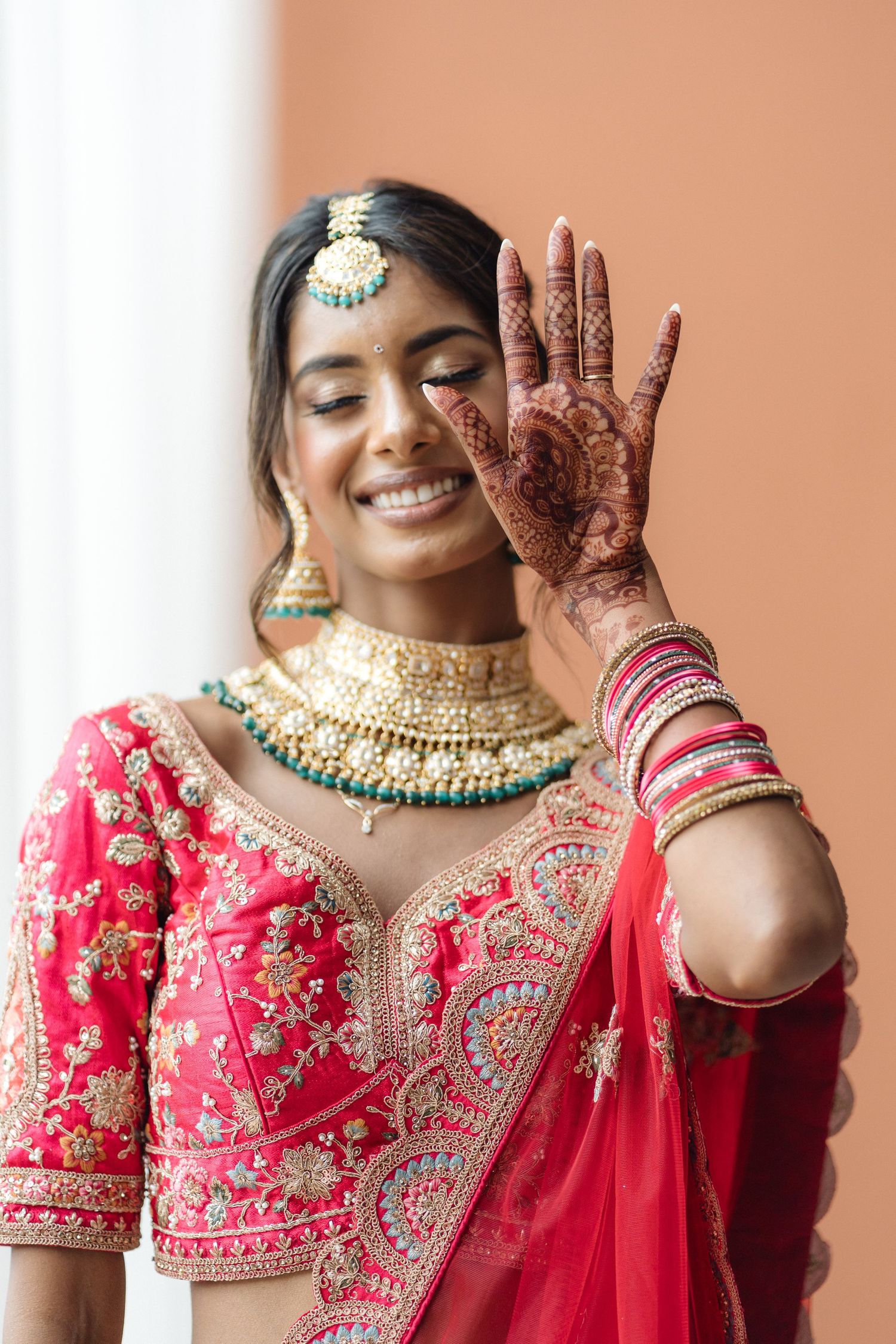 Close-up of traditional bridal jewelry and embroidered red wedding attire.
