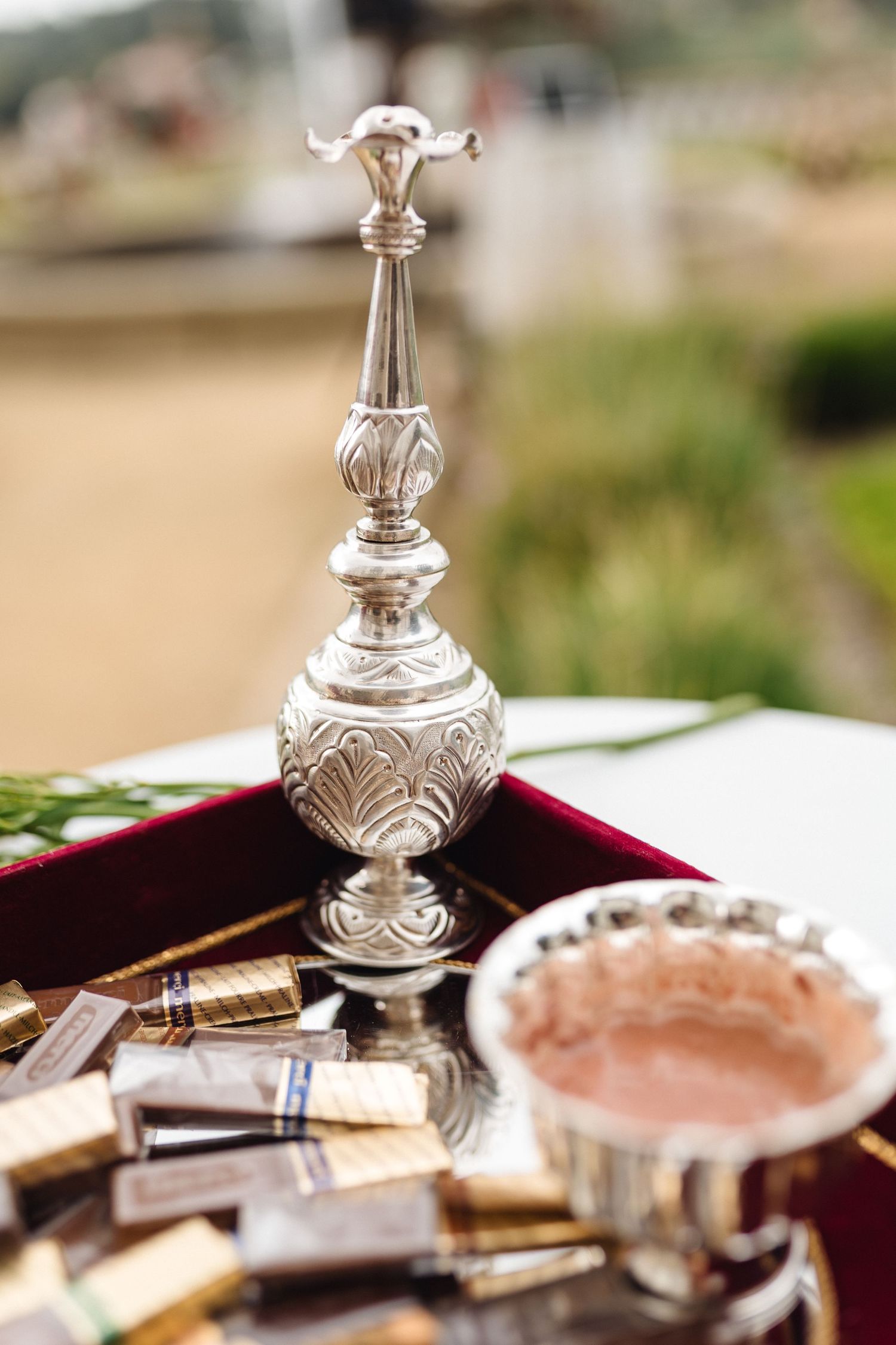 Ornate silver decorative items and place settings arranged on a burgundy tablecloth.