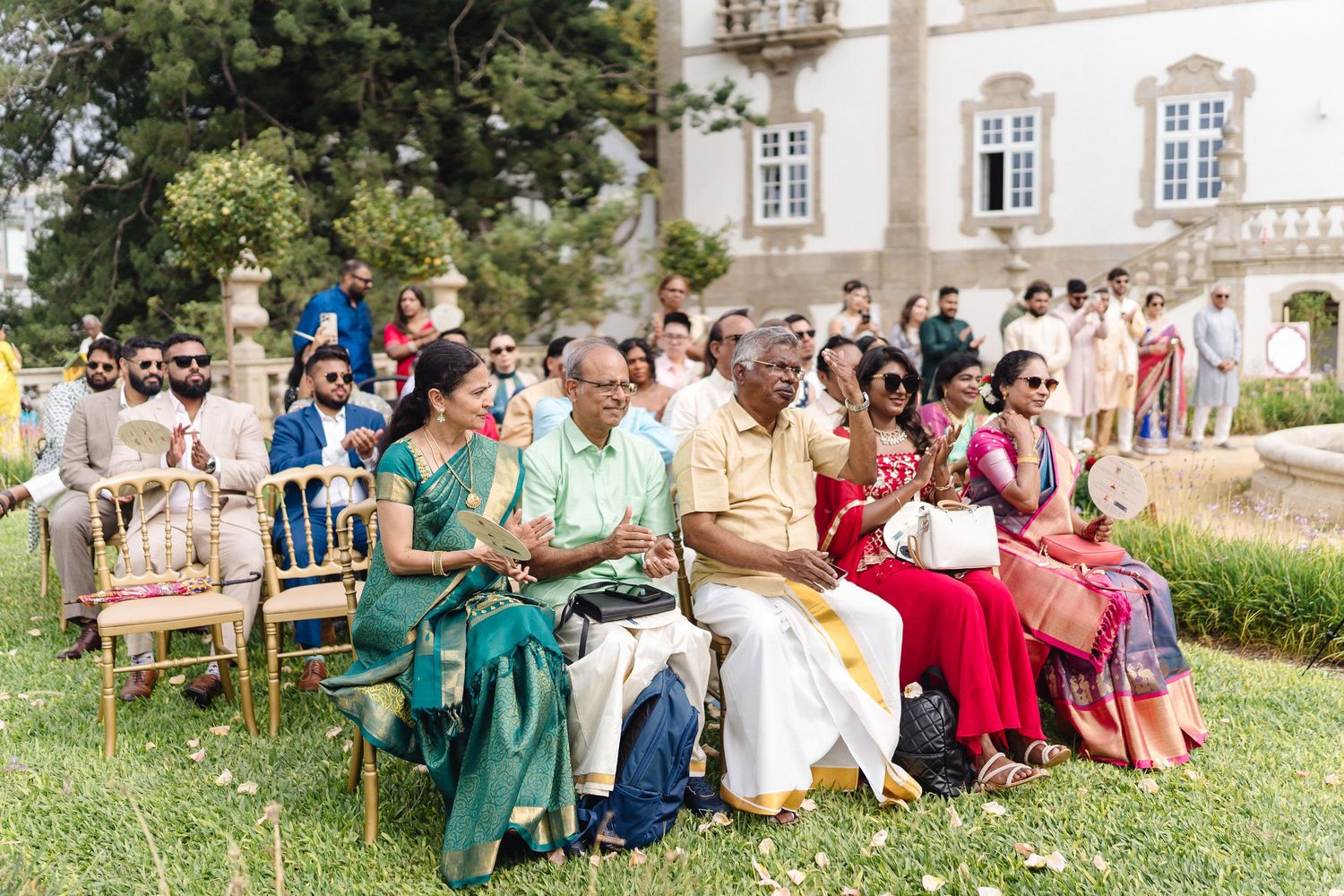 Wedding guests seated on lawn during outdoor celebration.