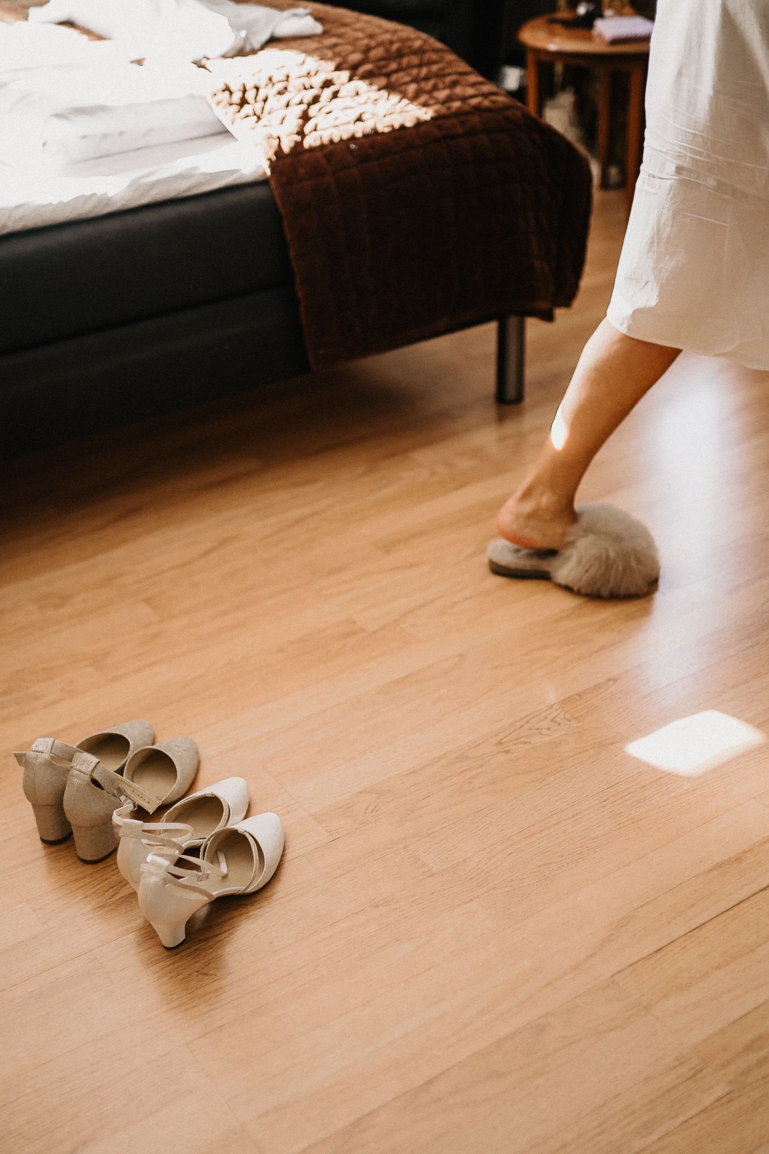 Pair of elegant beige wedding shoes on a light wooden floor.
