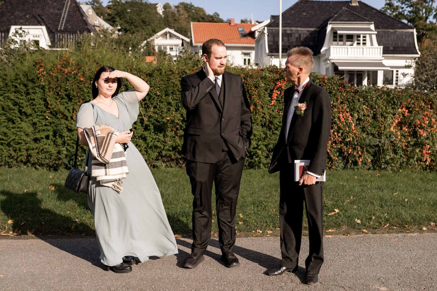 Wedding party members pose for outdoor photos on a sunny autumn day.
