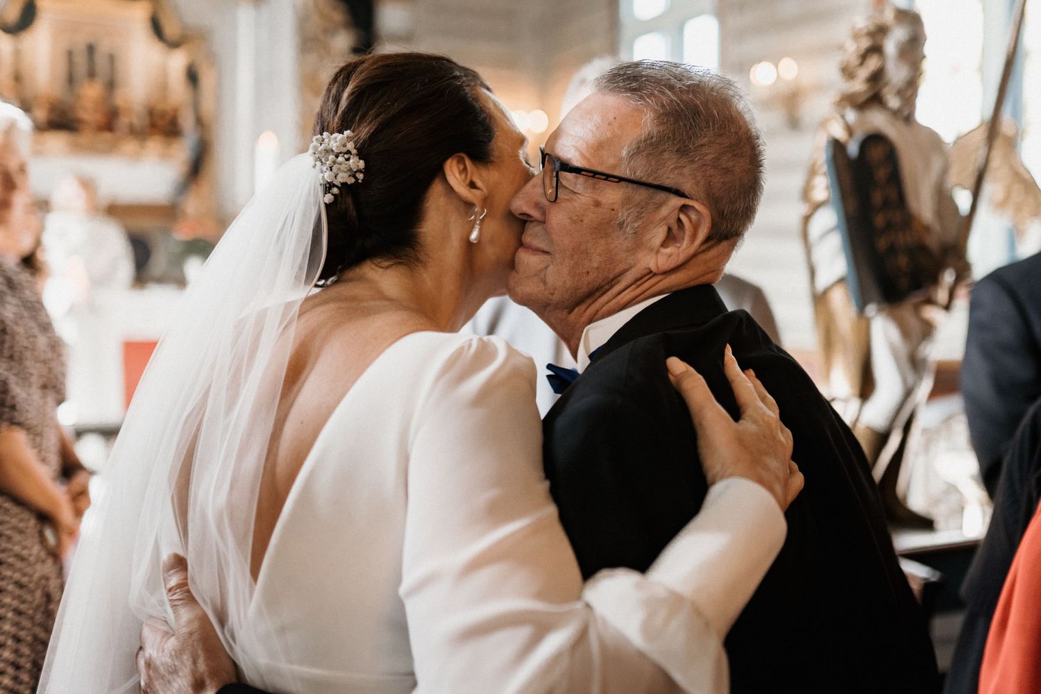 An intimate embrace between two wedding guests during an emotional moment at a church ceremony.