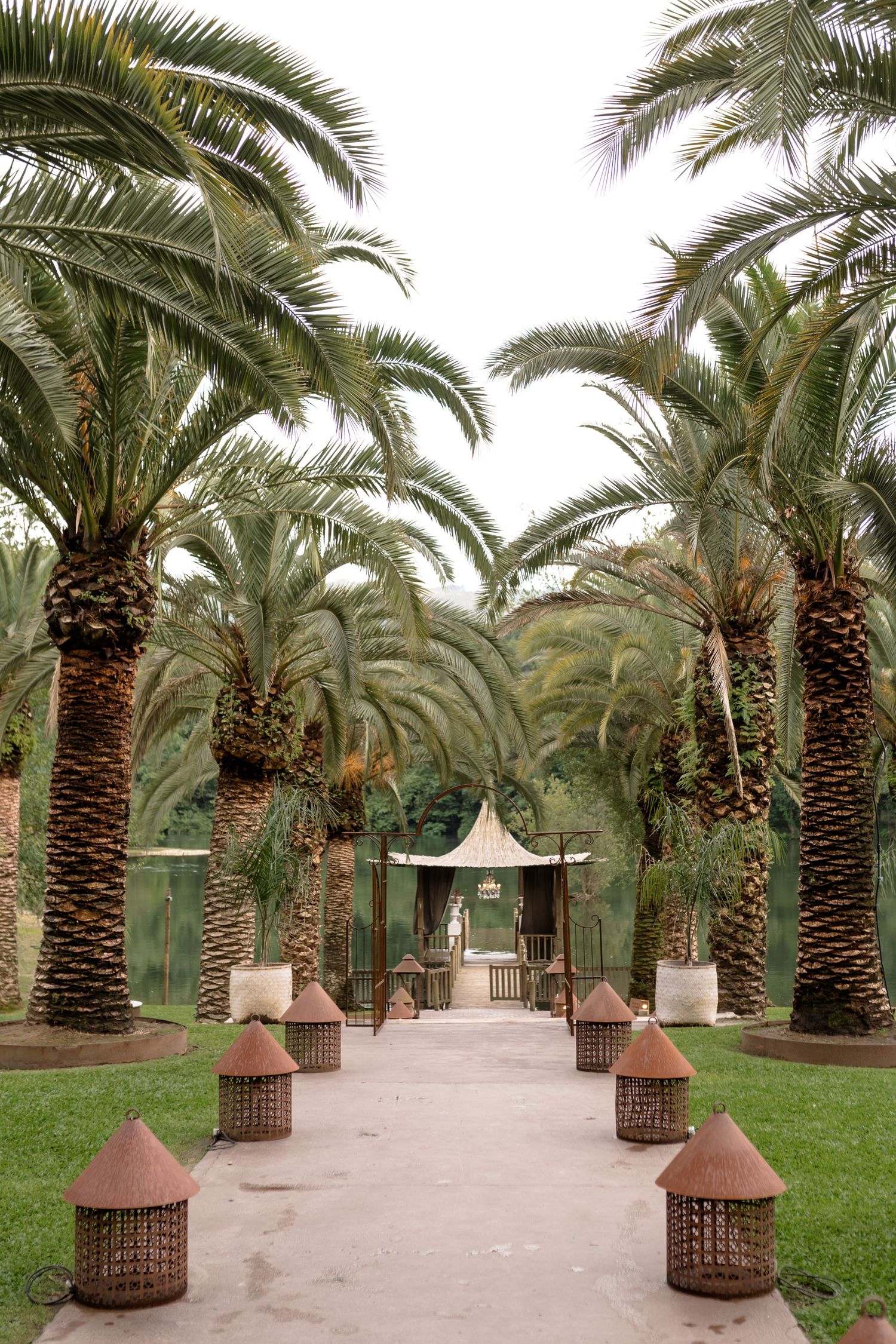 Palm tree-lined pathway with lanterns leading to an elegant white gazebo.