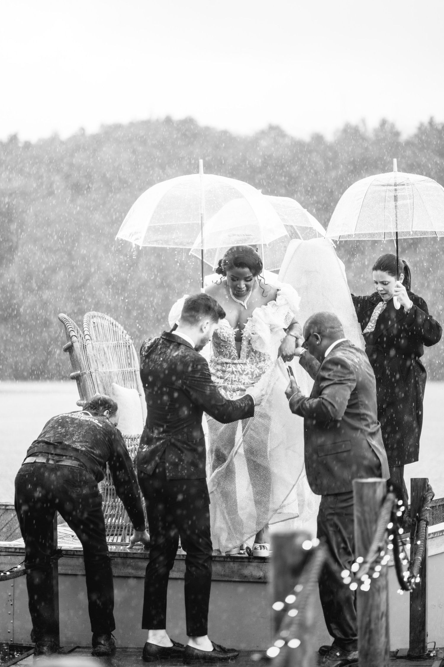 Black and white photo of wedding guests with umbrellas lined up along a railing.