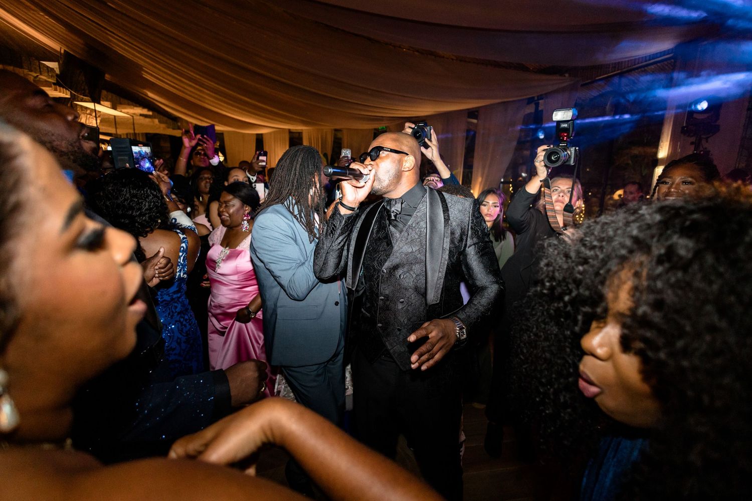Dimly lit reception venue with blue lighting and dancing guests on the dance floor.