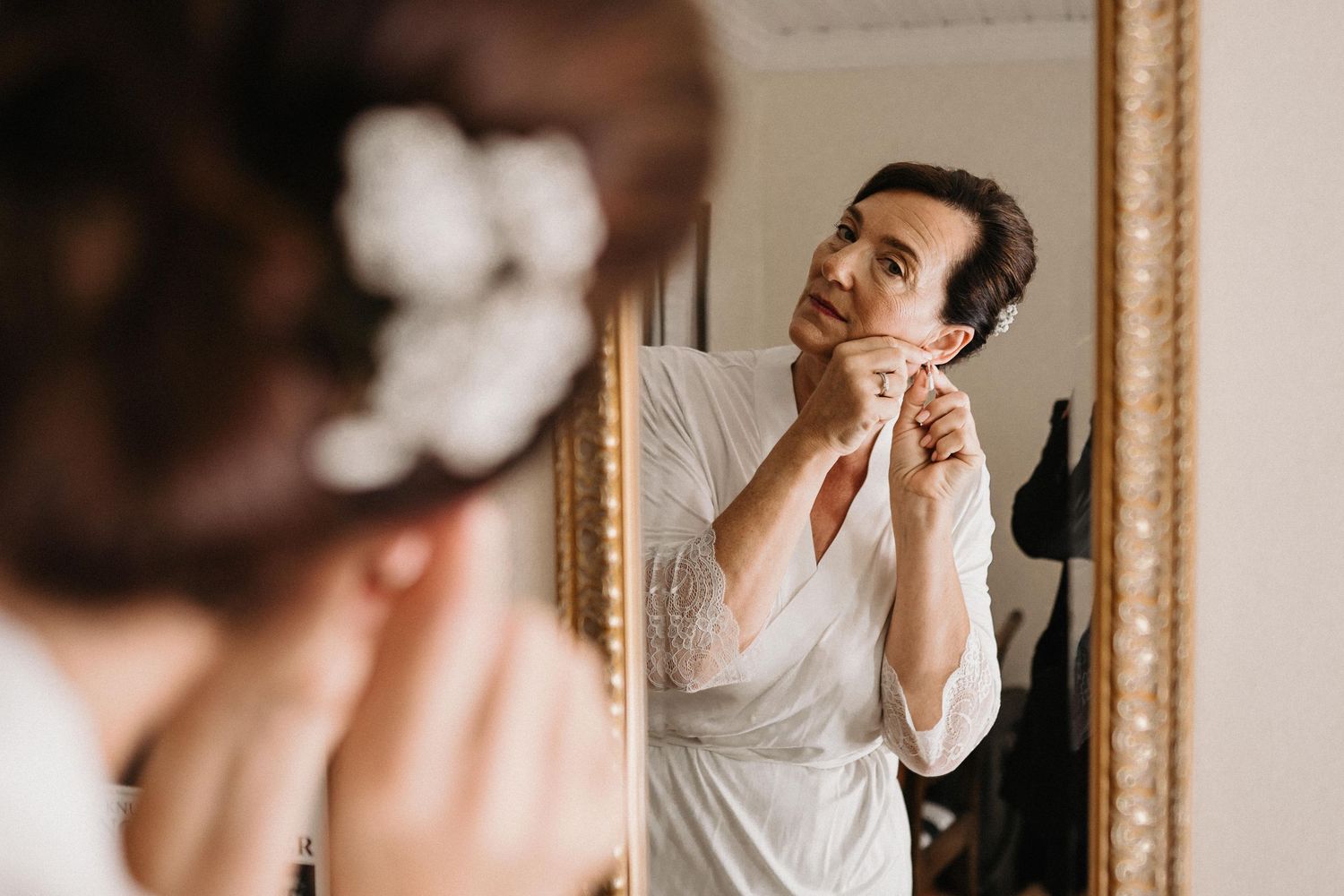 Person in white getting ready in front of an elegant vintage mirror.