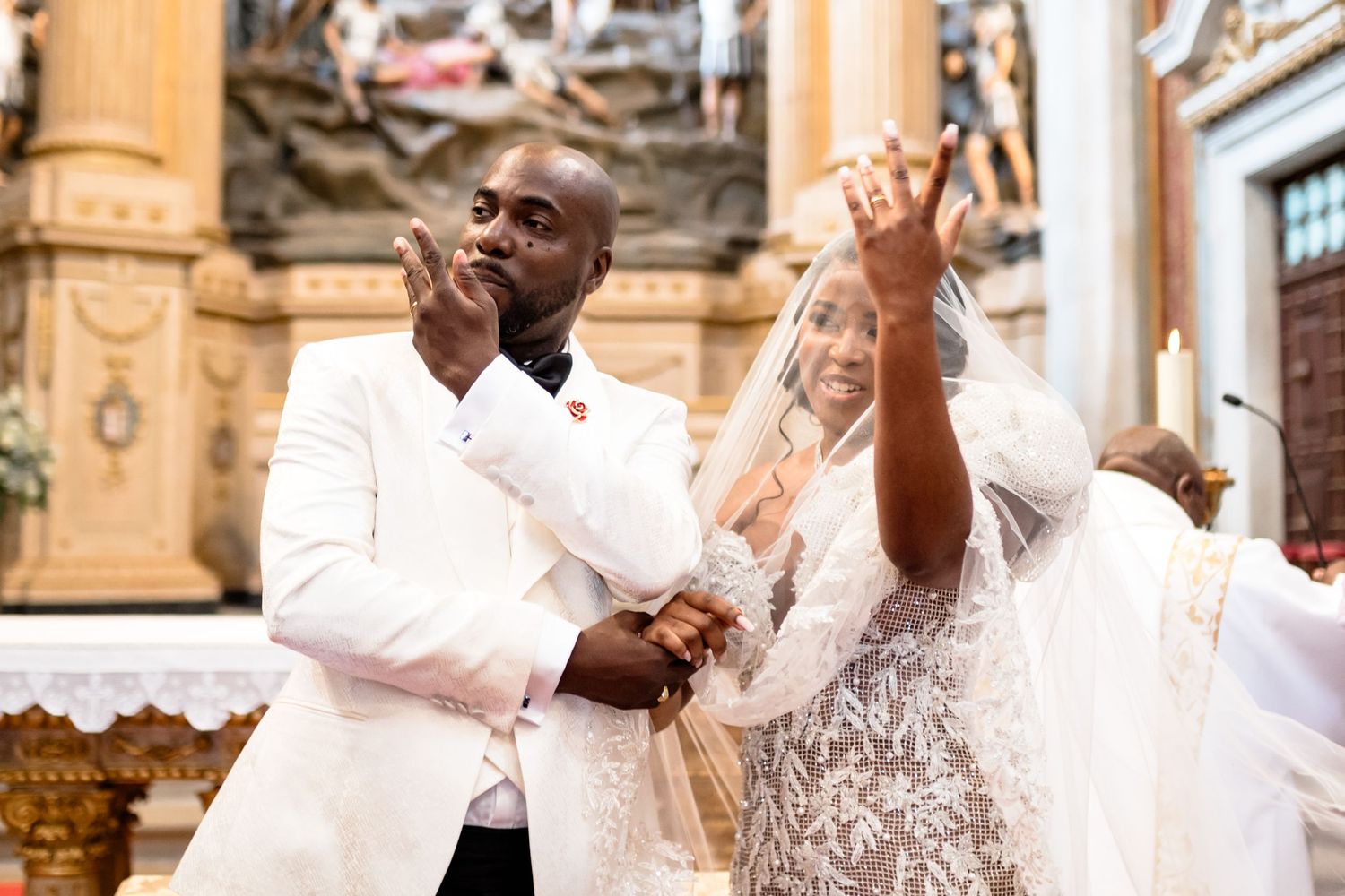 Wedding party members in white and formal attire pose together during an outdoor celebration.