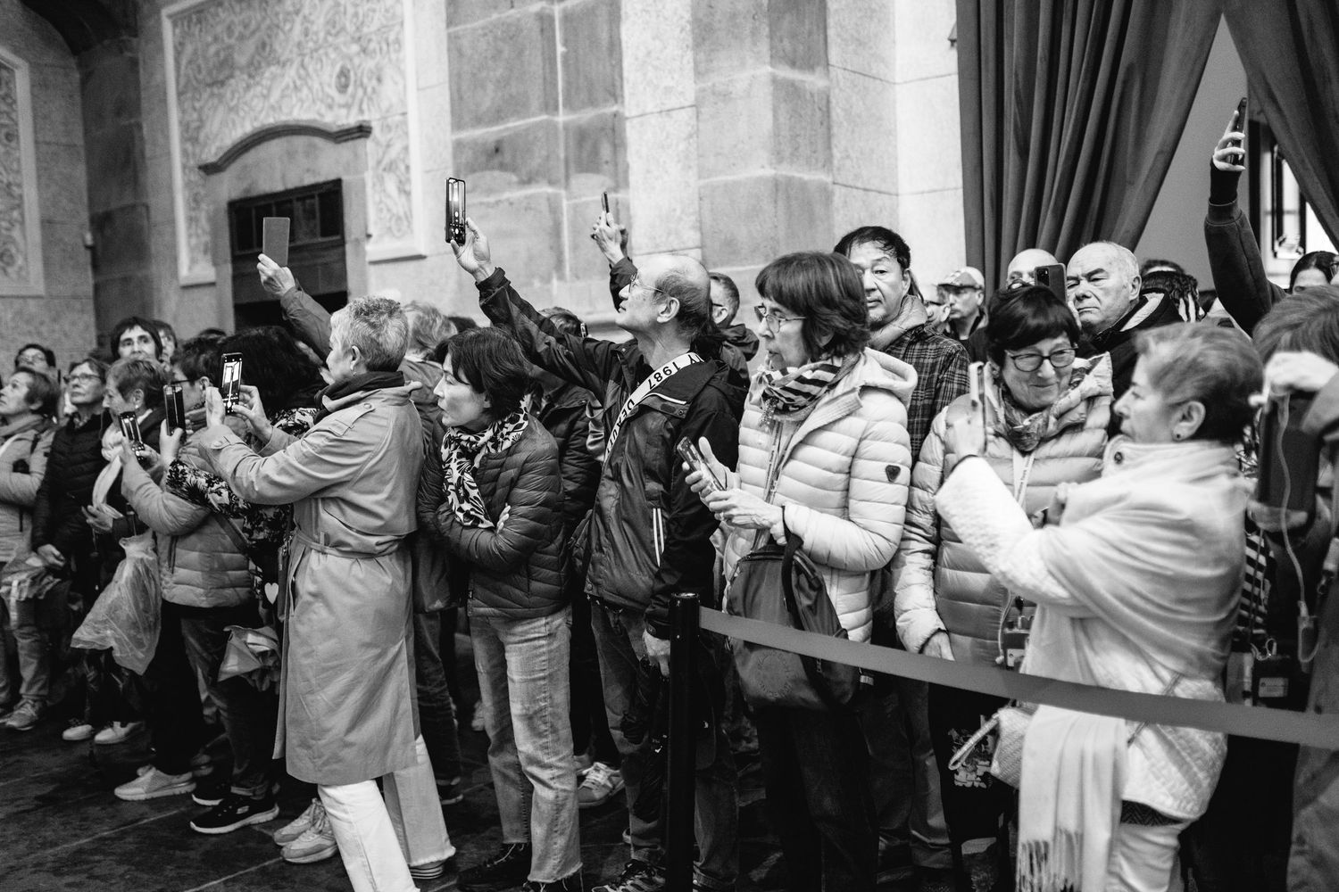 Wedding guests enthusiastically taking photos with their phones during a ceremony.