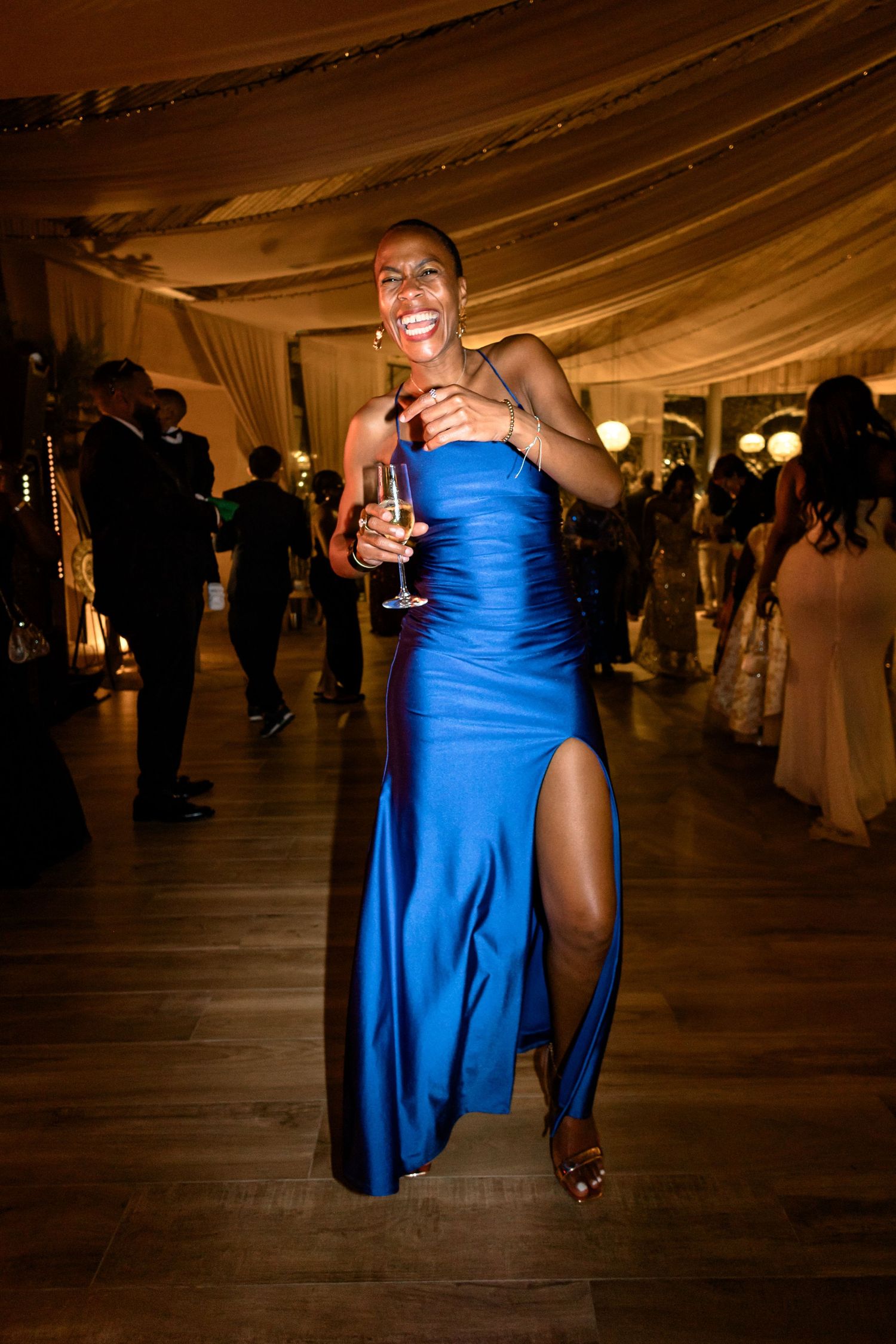 Wedding reception dancers in blue attire moving on the dance floor under draped fabric ceiling.