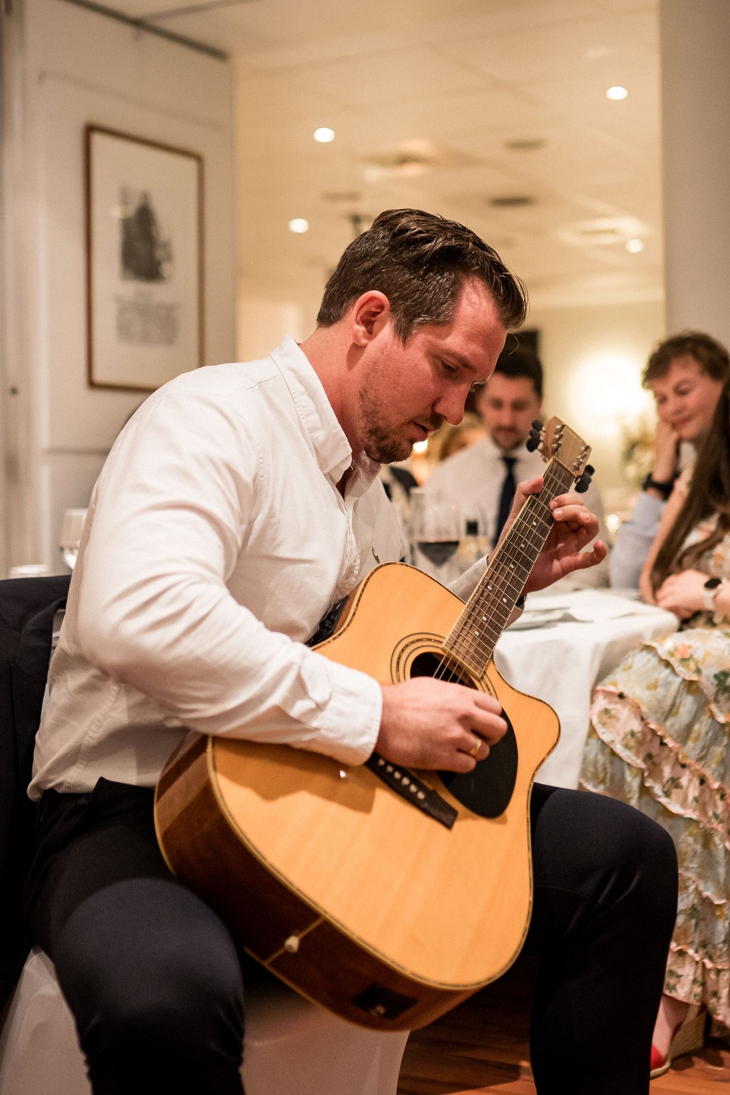 A musician plays acoustic guitar during an indoor performance.