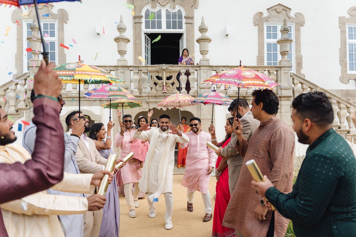 Festive outdoor celebration with pink parasols and traditional Indian wedding attire.