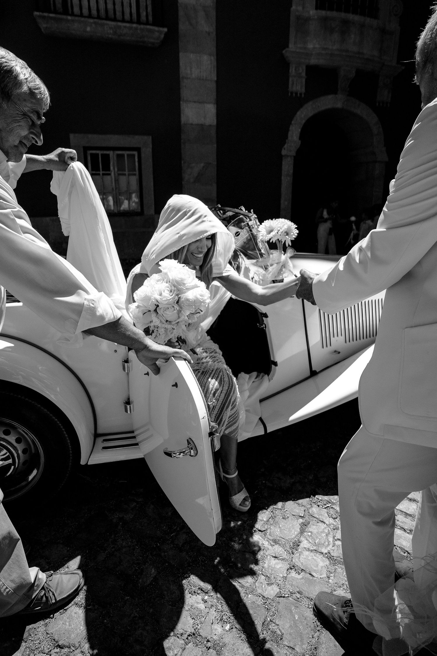 Wedding party members in white attire pose playfully together.