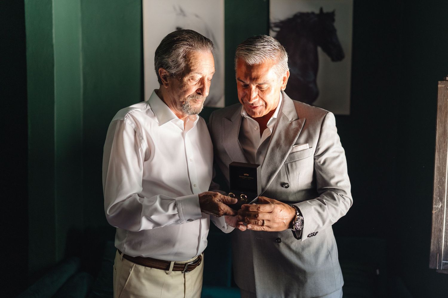People in white shirts conversing in an intimate setting with green walls.