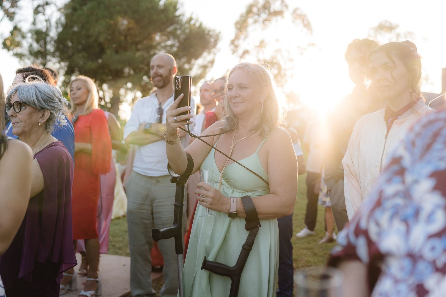 Wedding guests mingle and chat during an outdoor sunset reception celebration.