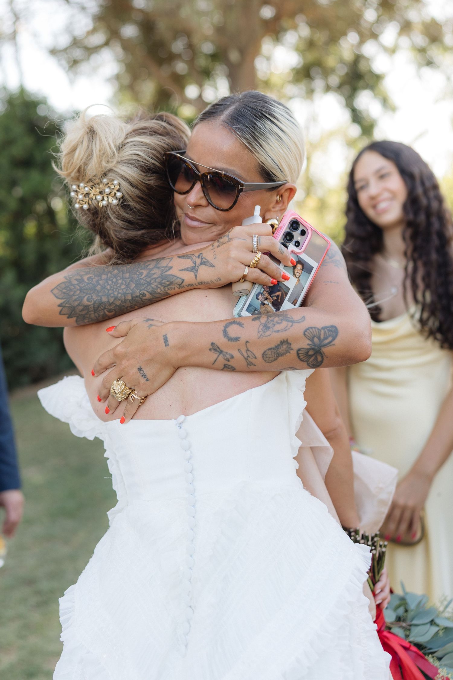 Emotional wedding moment captured with warm embraces and joyful tears during an outdoor ceremony.