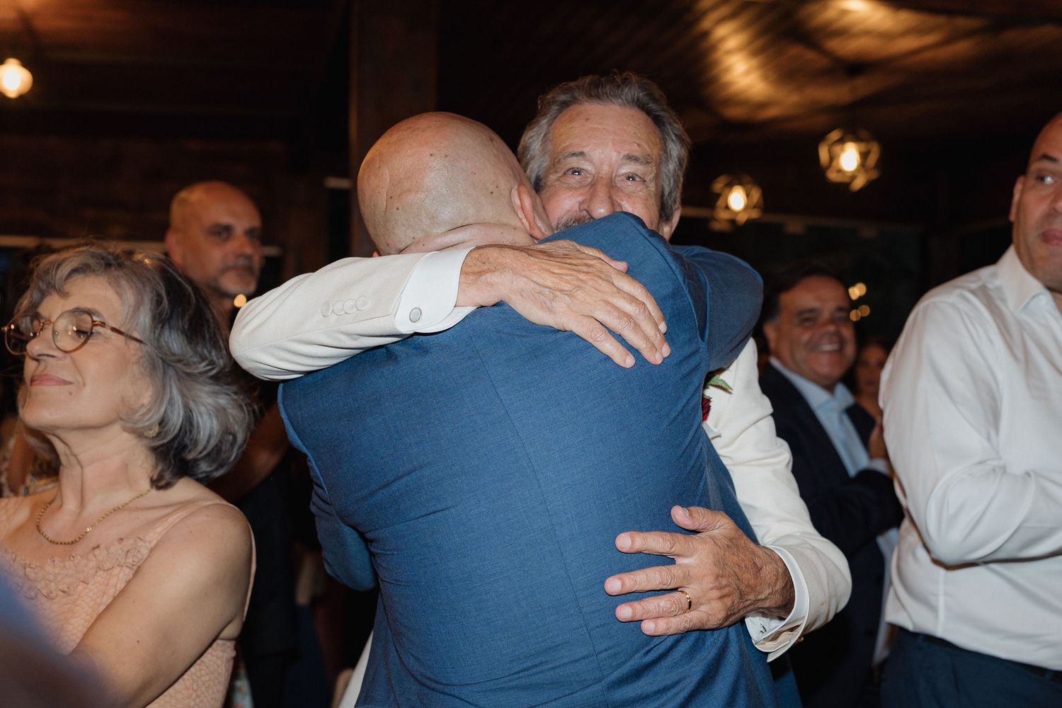 Wedding guests sharing warm embraces during reception dance celebrations.
